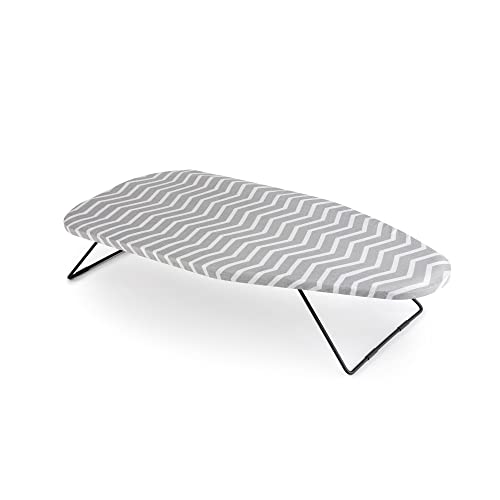 Una pequeña tabla de planchar con un patrón de zigzag gris y blanco en la funda.