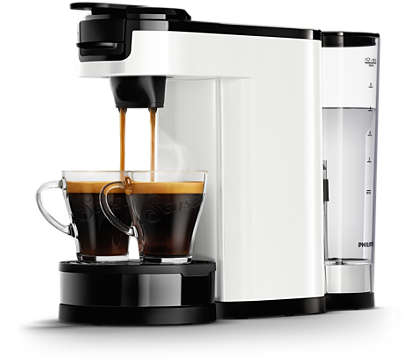 Wit en zwart koffiezetapparaat dat koffie in twee glazen kopjes zet. Transparante watercontainer zichtbaar.