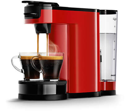 Rode koffiemachine met twee kopjes. Koffie wordt in de kopjes gegoten.