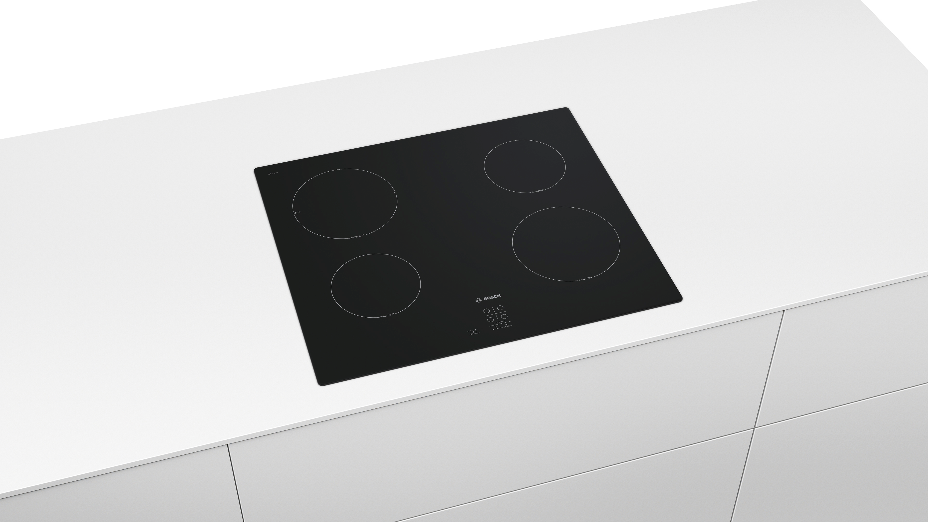 Black stovetop with four burners on a white countertop.