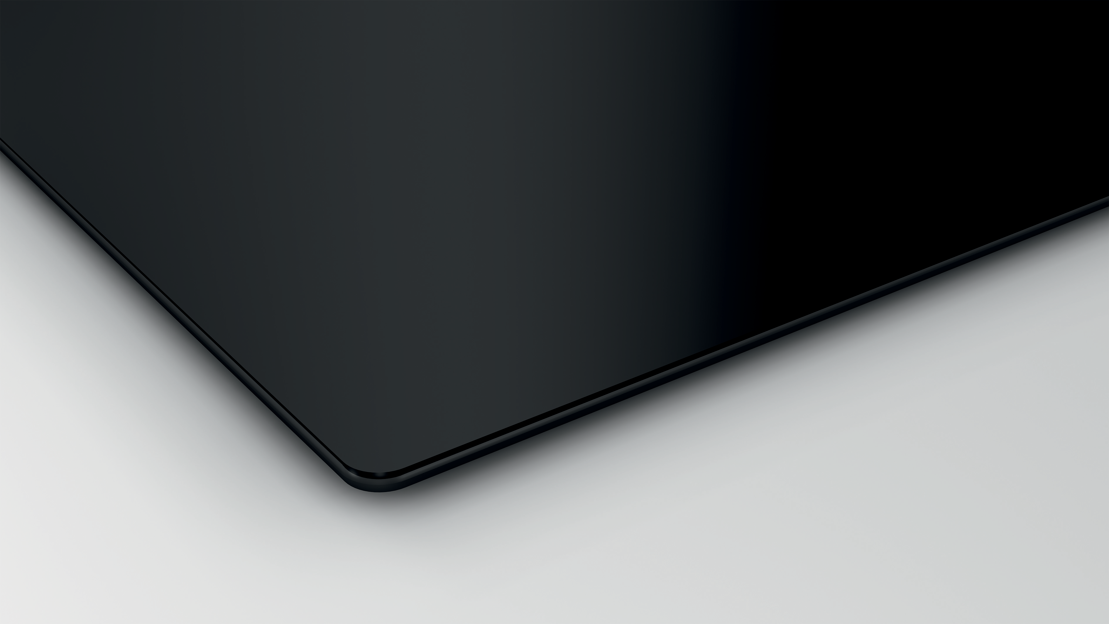 Black glass cooktop, slightly angled, showing a smooth, reflective surface.