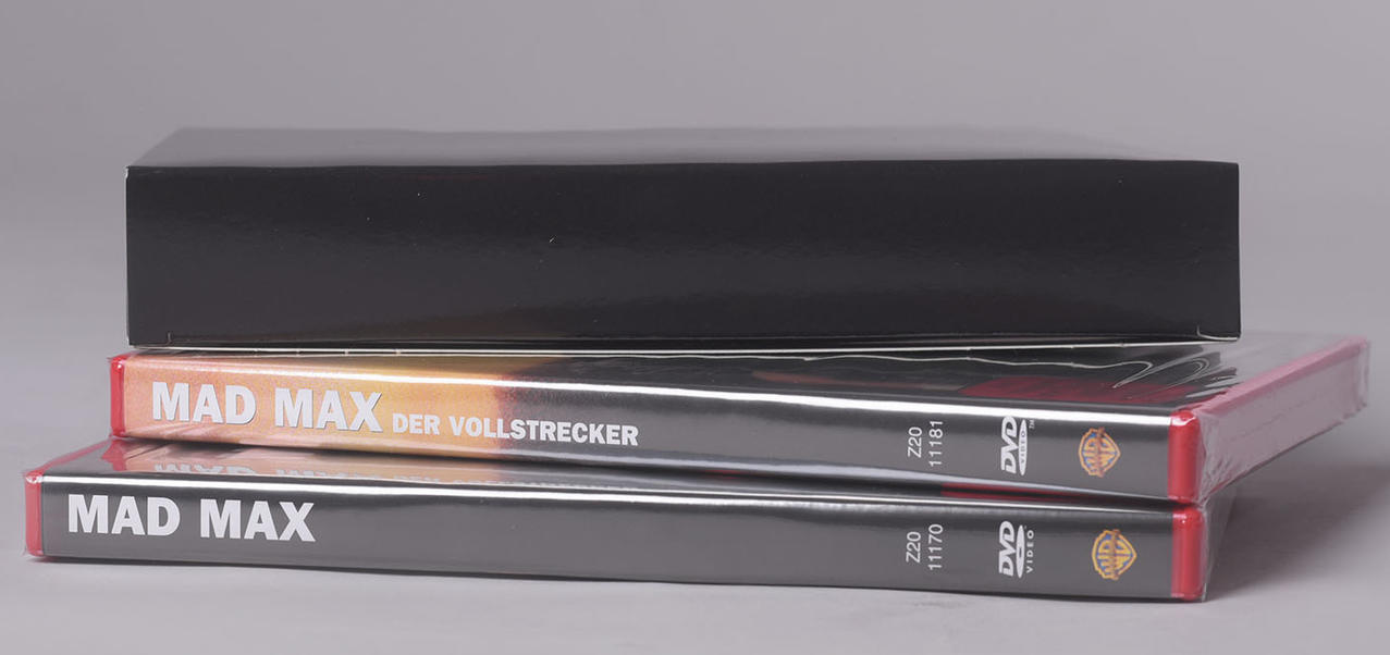 Zwei gestapelte DVDs: 'Mad Max' und 'Mad Max: Der Vollstrecker' in einer schwarzen, glänzenden Box.