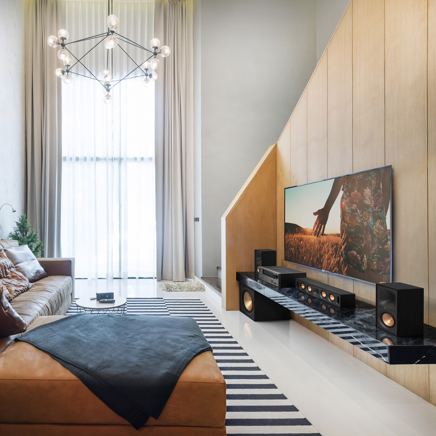 Moderne woonkamer met bruine leren bank, tv en een zwart-wit gestreept tapijt.