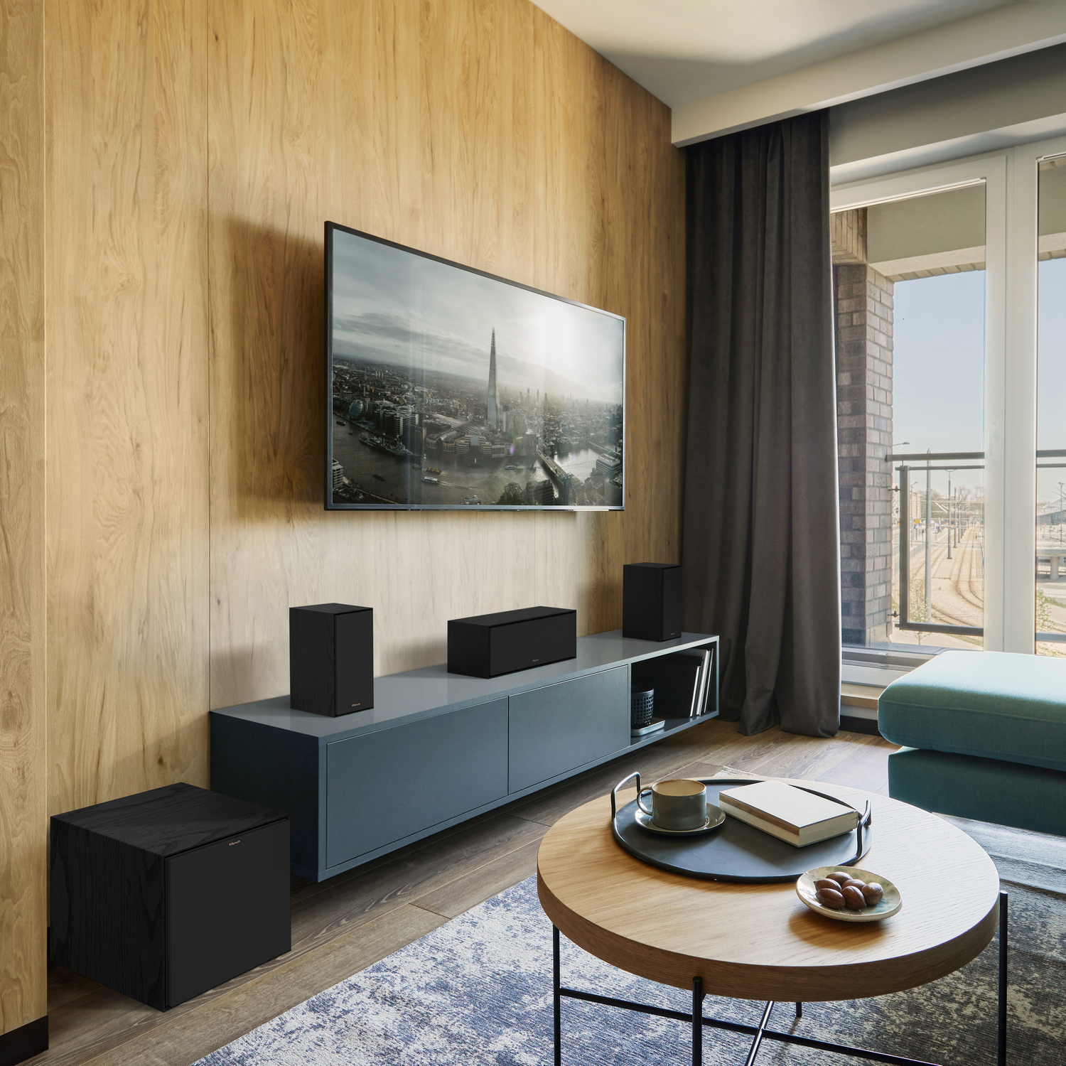 A modern living room with a TV on the wall and speakers. A coffee table with decor.