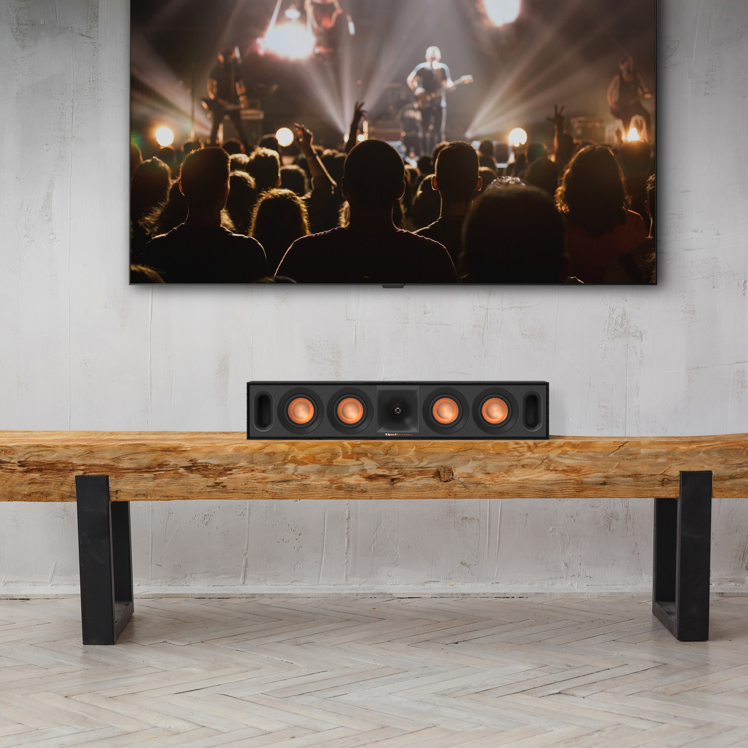 Woonkamer met een tv, soundbar en een houten bank. Mensen op de achtergrond.
