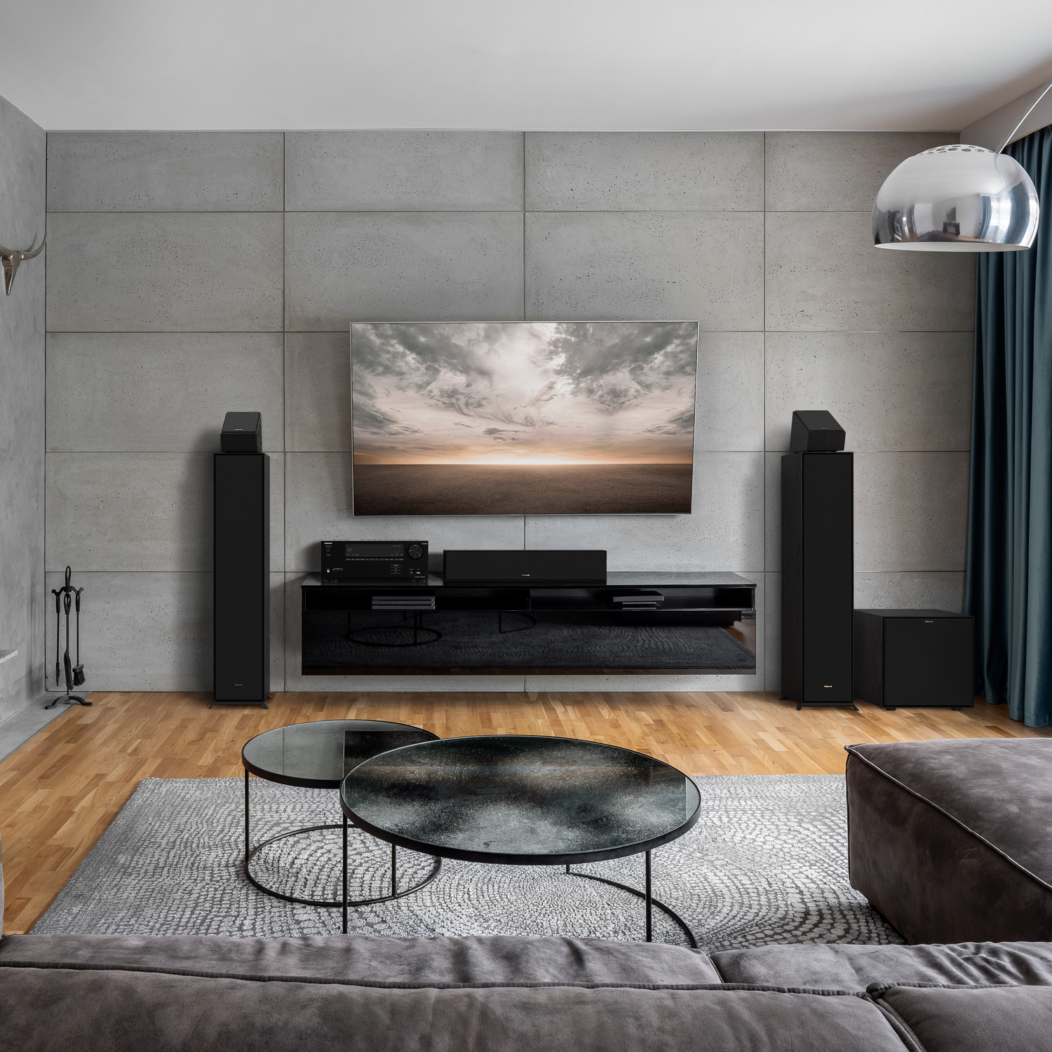 Living room with a TV mounted on a concrete wall and black furniture.