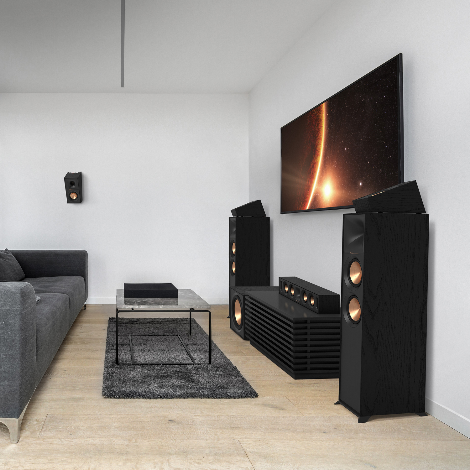 A modern living room with a TV, speakers, and soundbar, a coffee table, and a grey couch.