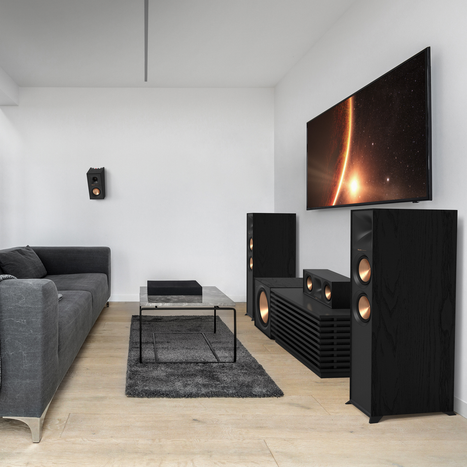 Living room with a TV, speakers, sofa, coffee table, and a rug.