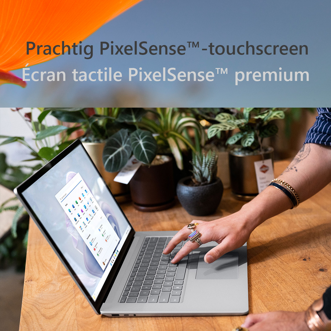 Personne utilisant un ordinateur portable. Le texte à l'écran indique 'Prachtig PixelSense touchscreen'. Plantes et une table en arrière-plan.
