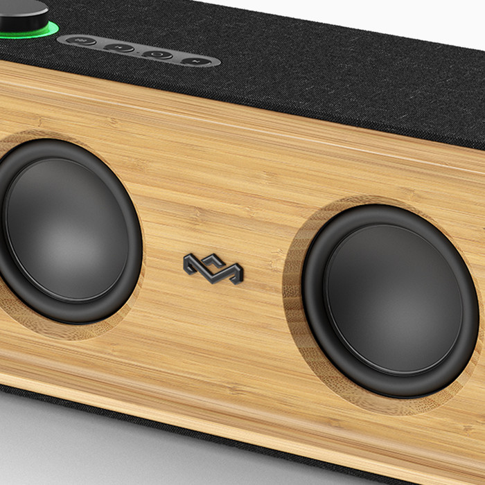 Close-up of a wooden speaker with two black speakers and a dark fabric top with control buttons.