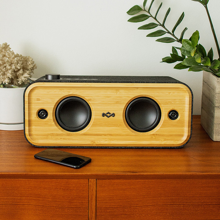 A wooden speaker with two black speakers, and a phone on a wooden surface.