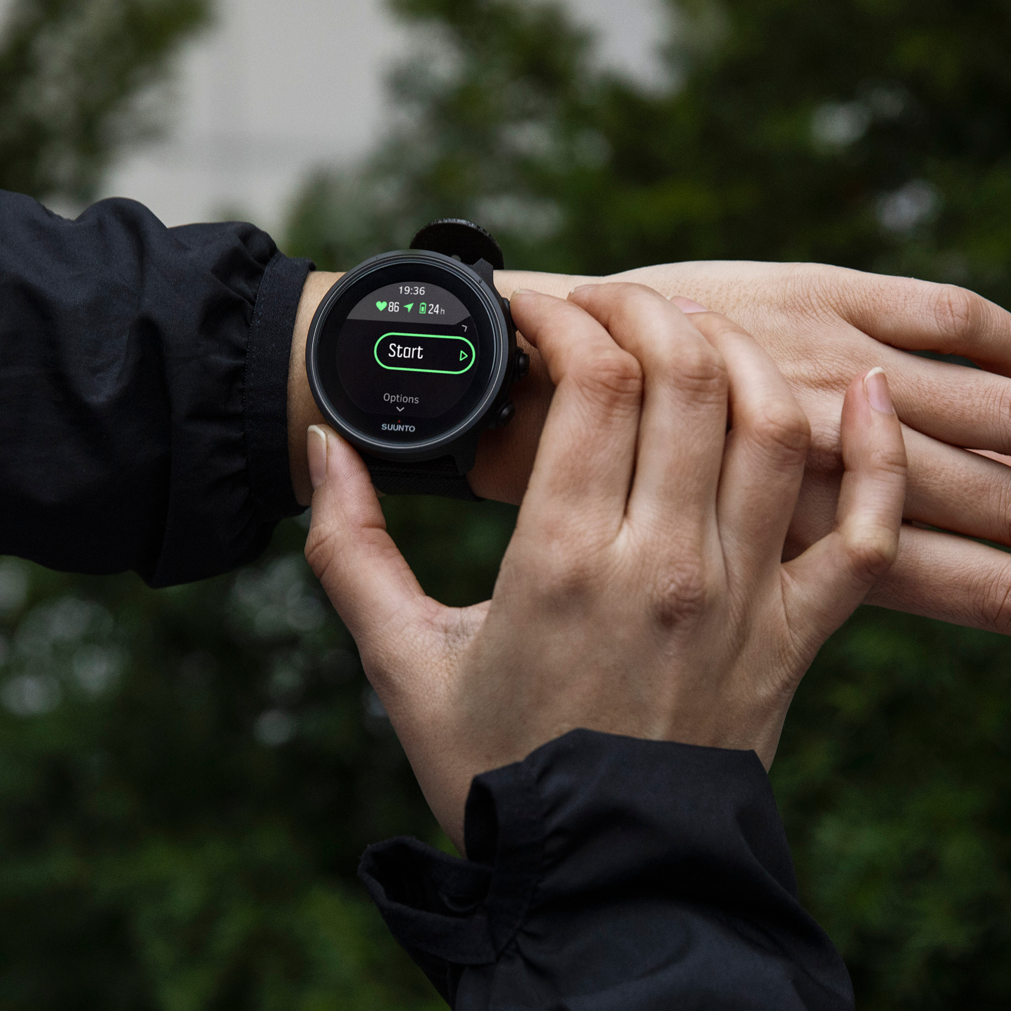 Hände einer Person mit schwarzer Smartwatch, Start-Knopf auf dem Bildschirm.