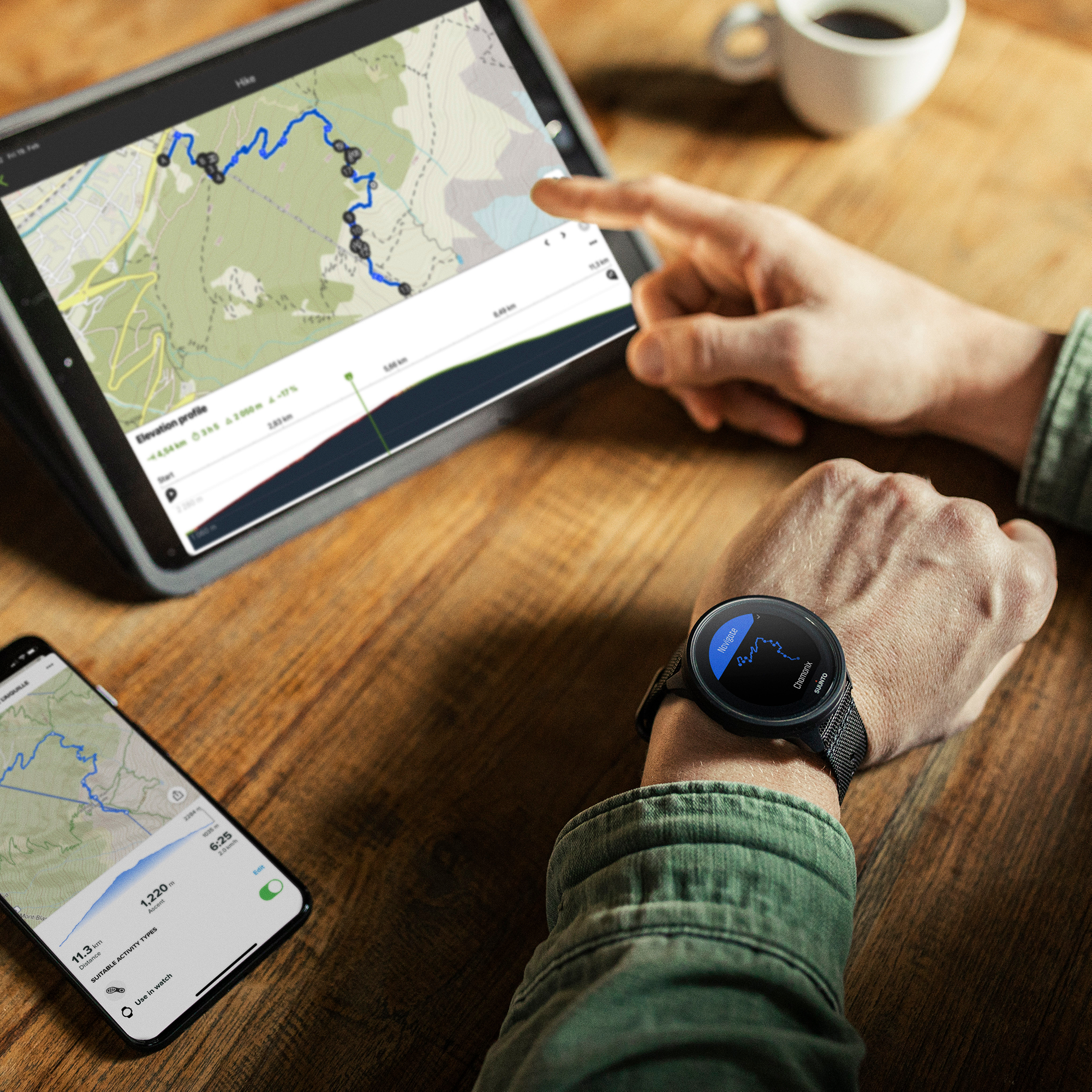 Eine Person benutzt ein Tablet, ein Smartphone und trägt eine Smartwatch, alle zeigen eine Karte.