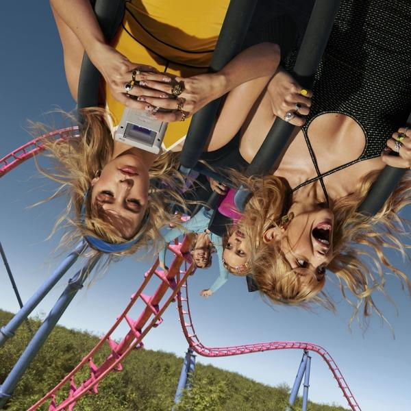 Deux femmes à l'envers dans des montagnes russes. Elles portent des bagues et ont l'air excitées.
