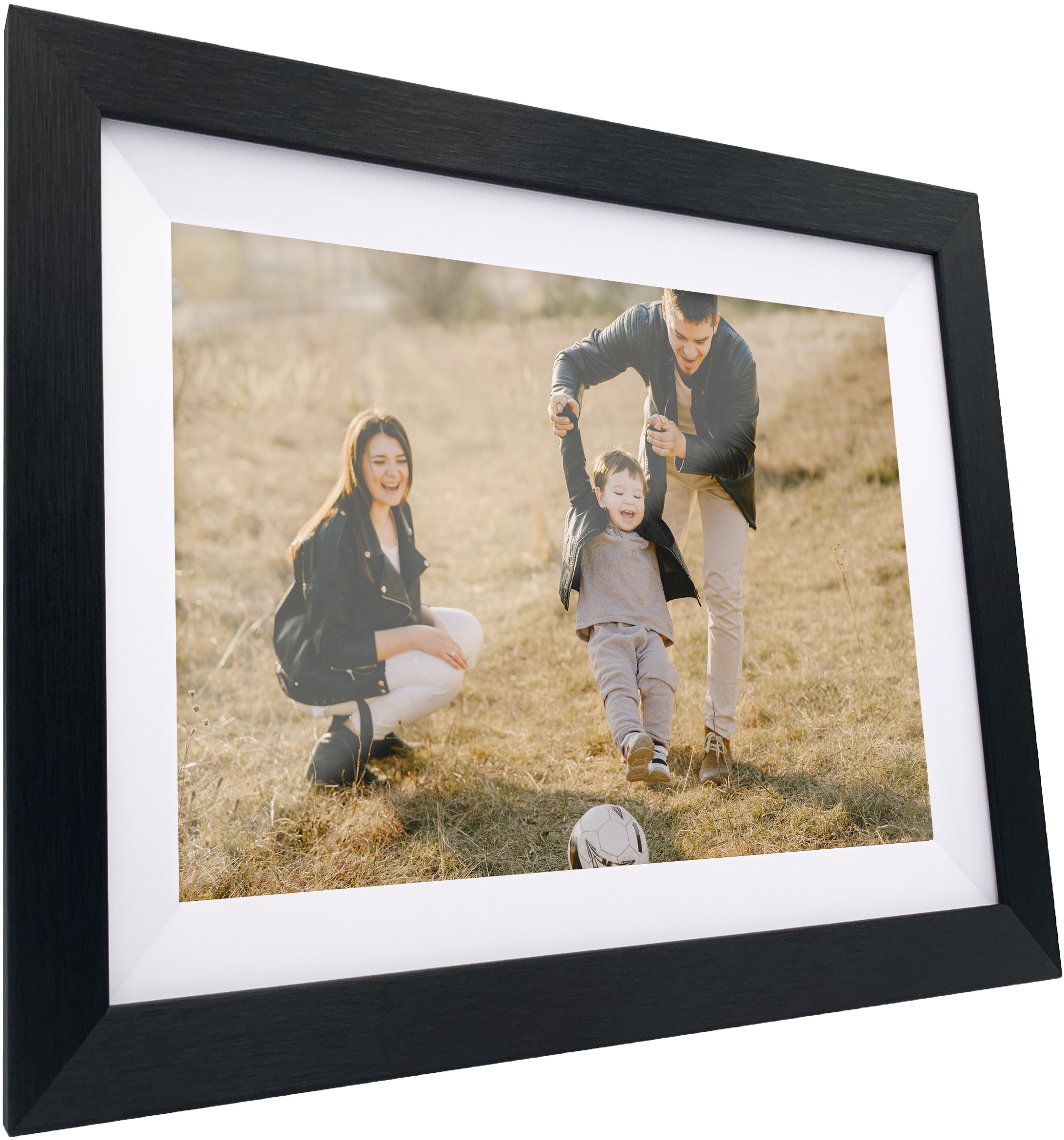 Une famille jouant dans un champ, encadrée dans un cadre photo noir. Un homme balance un enfant, une femme regarde.