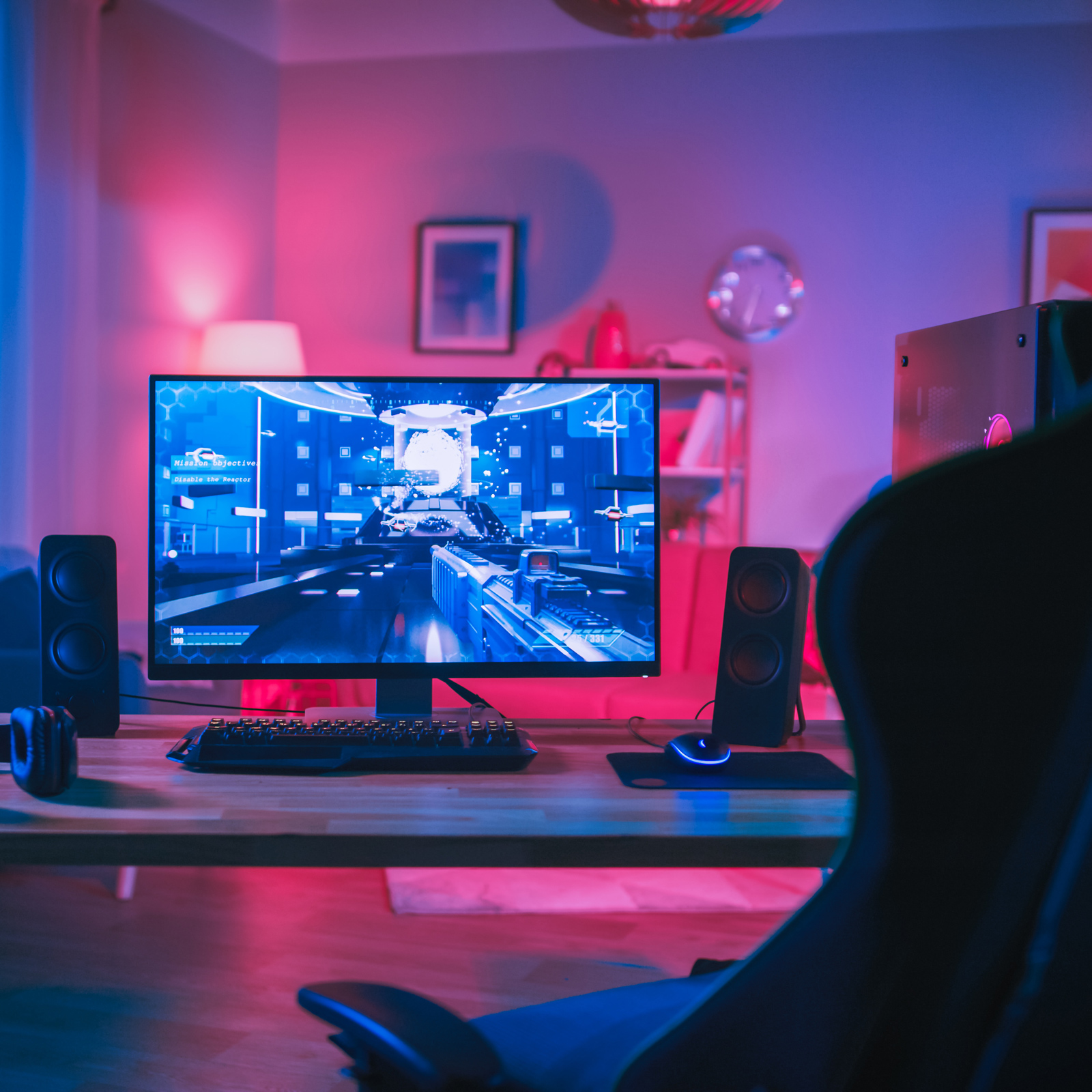 Játékbeállítás monitorral, játékkal, hangszórókkal, billentyűzettel és egérrel egy szobában.