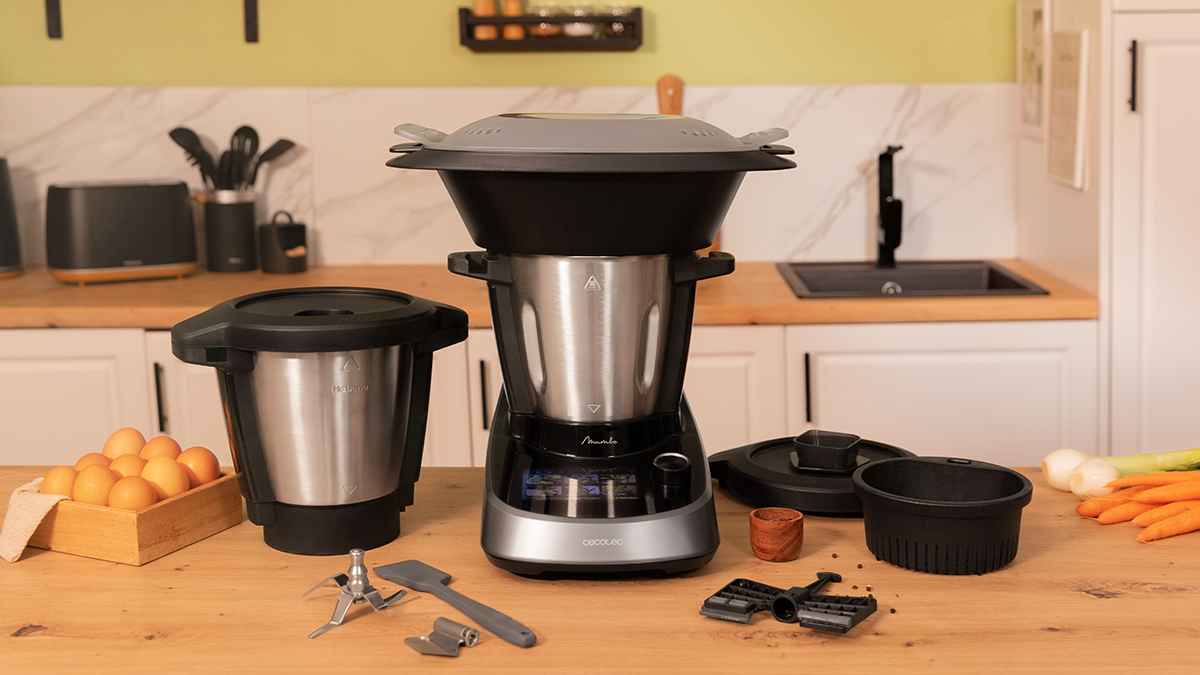 Robot de cocina Cecotec Mambo con accesorios. En una encimera de madera, con ingredientes y utensilios.