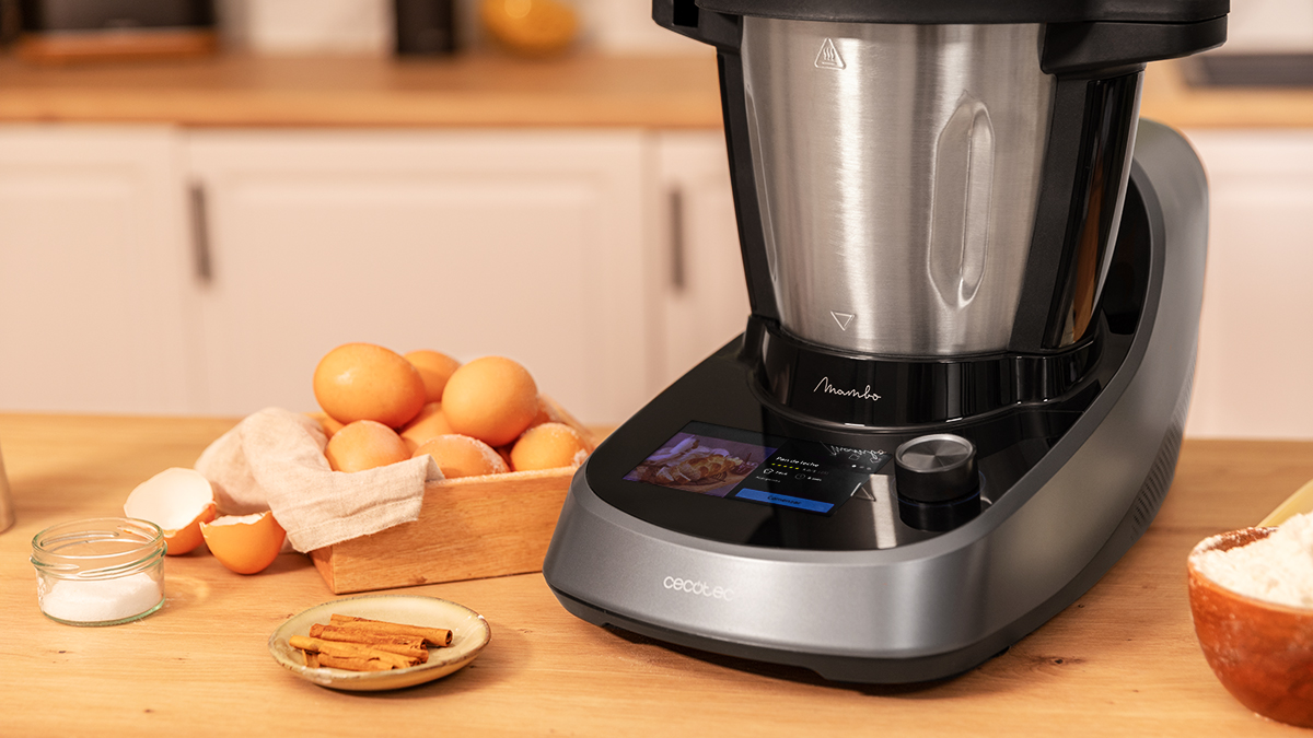 Un electrodoméstico de cocina con pantalla, junto a una caja de madera con huevos y canela.