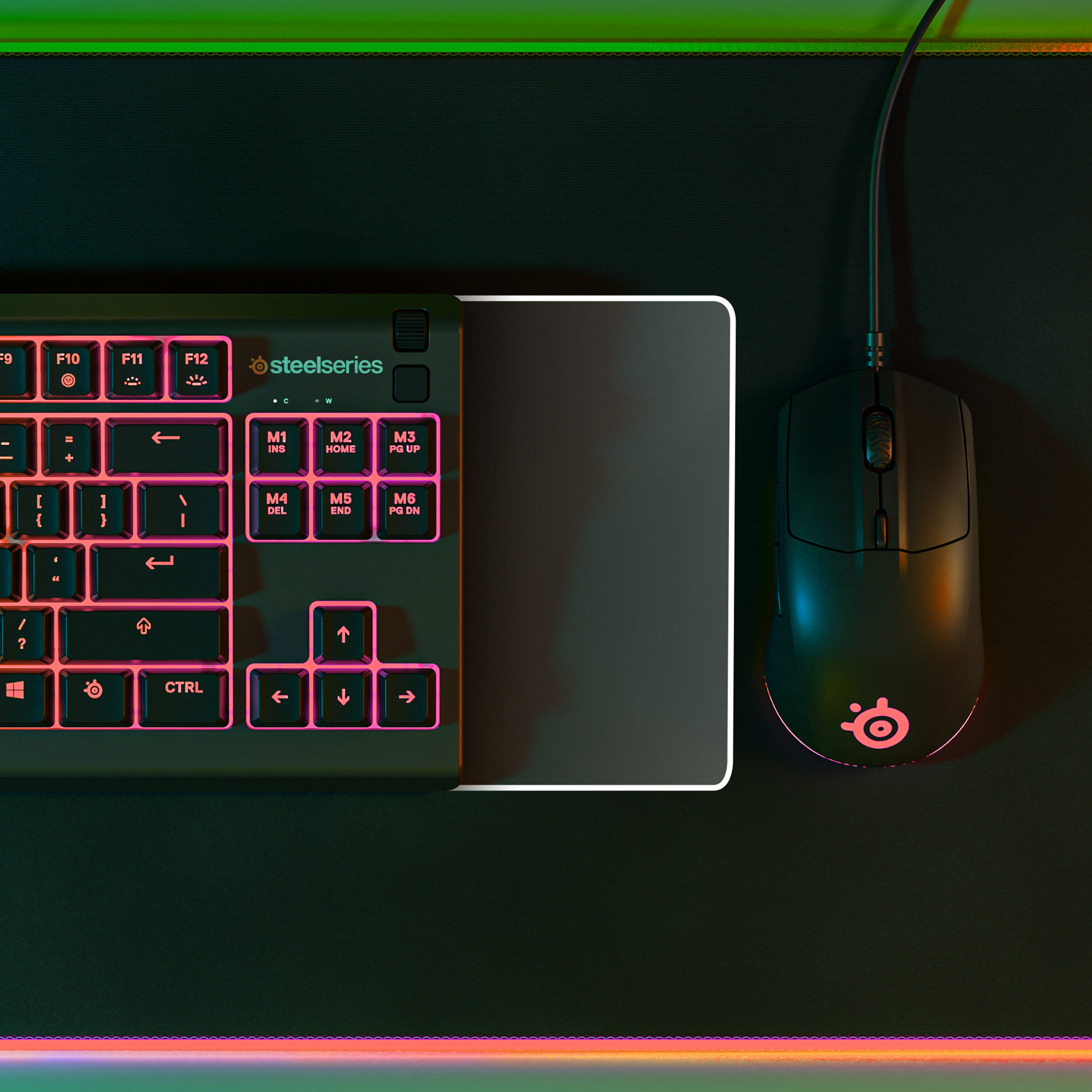 Black keyboard and mouse on a black mousepad, illuminated with pink lights.