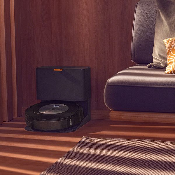 Schwarzer Roboter-Staubsauger in seiner Ladestation, neben einem Sofa.