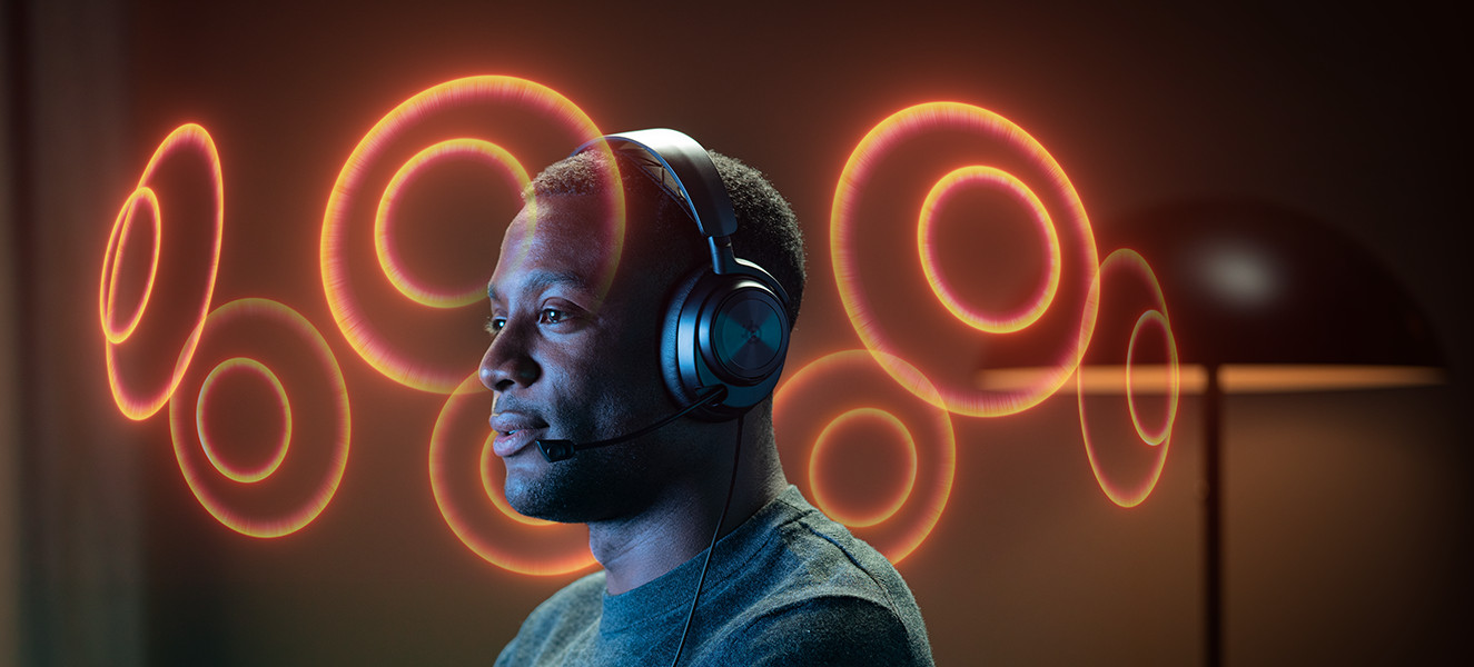 A man wearing a headset is gaming, with orange circles around him.