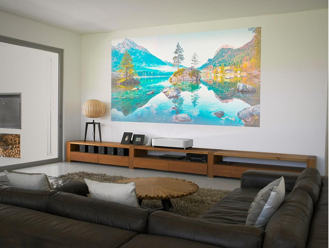 Projisziertes Bild einer Landschaft an einer weißen Wand in einem Wohnzimmer.
