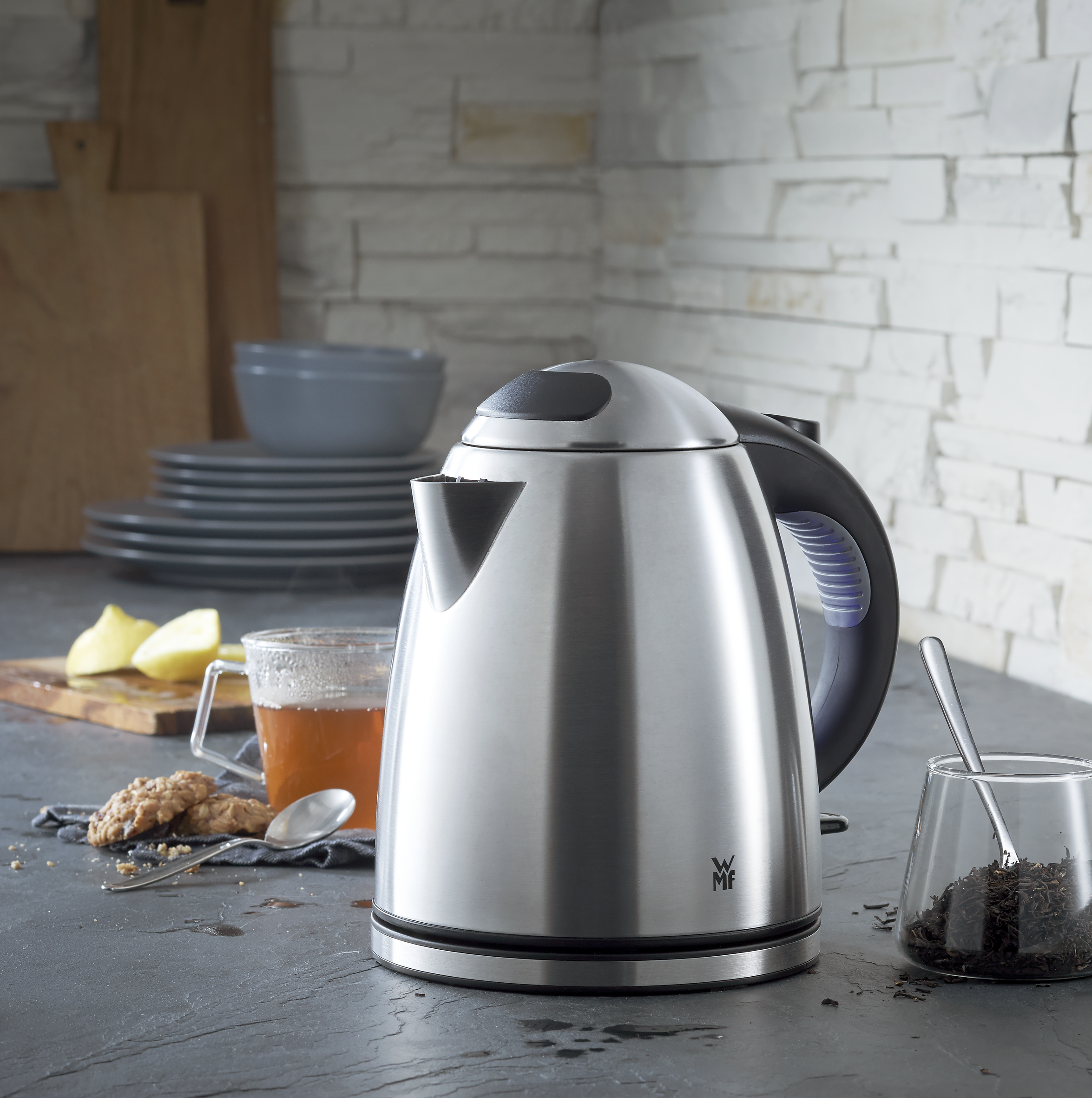 Hervidor eléctrico de acero inoxidable con té y galletas en una encimera.