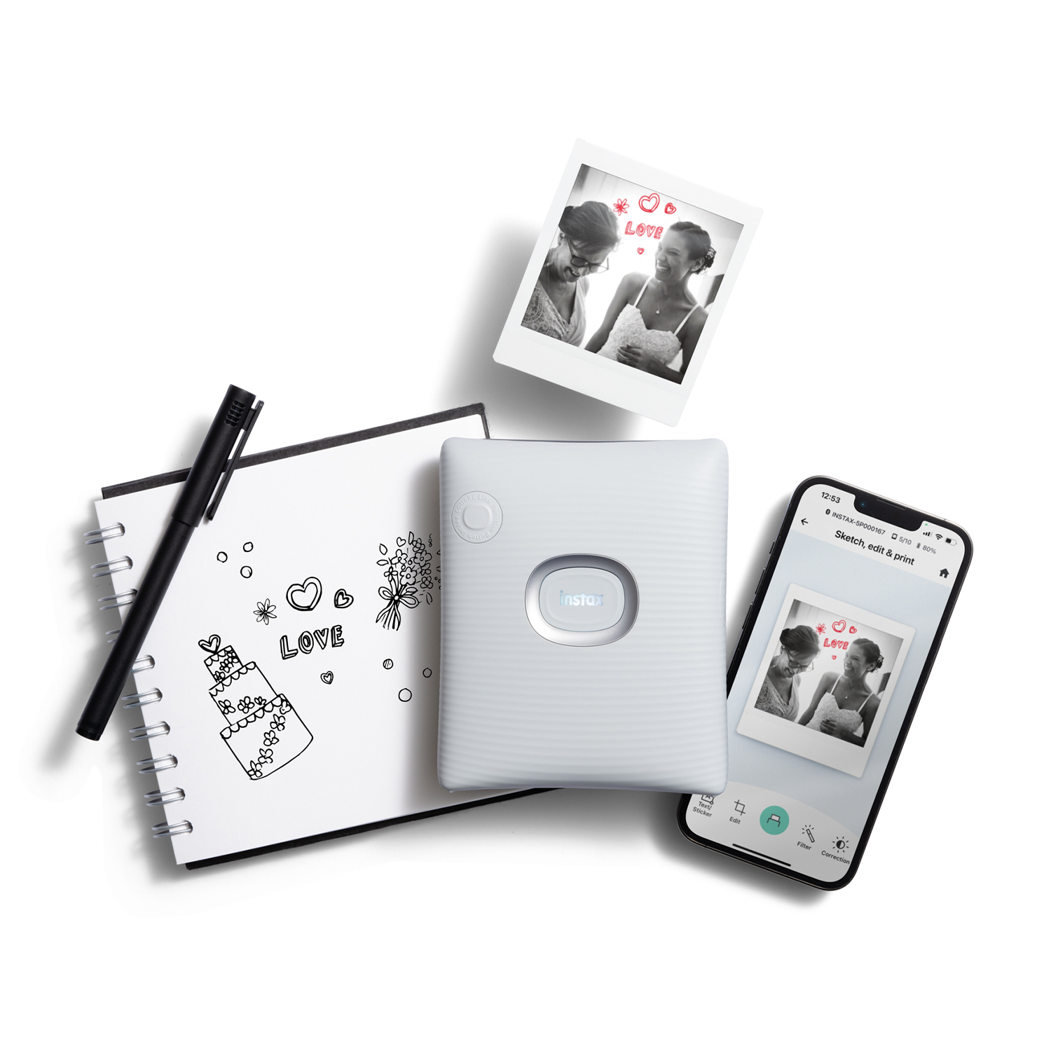 Una stampante Instax bianca, foto, taccuino e penna, disposti su una superficie bianca.