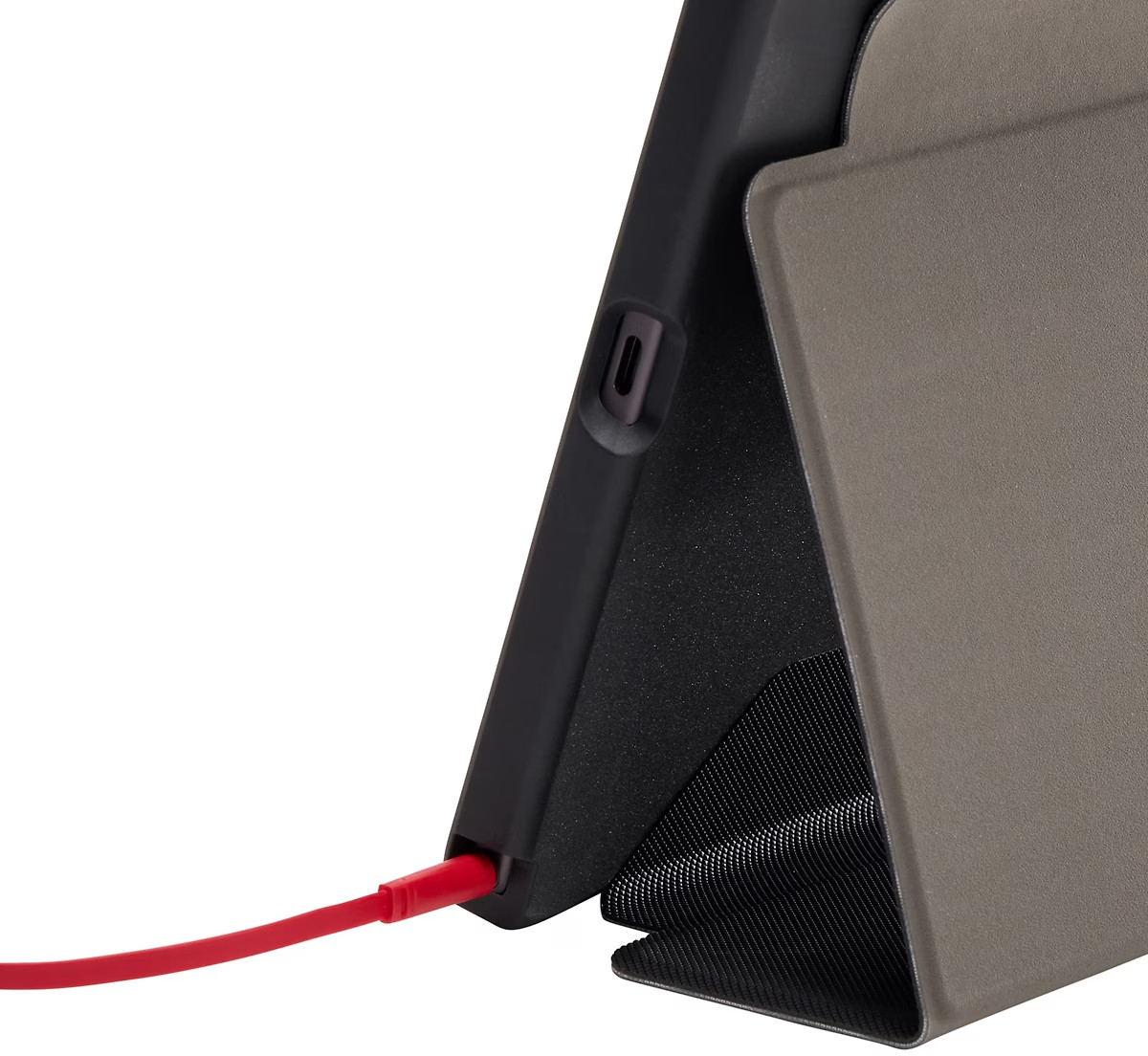 Close-up of a tablet with a charging cable connected to the device, on a light gray cover.