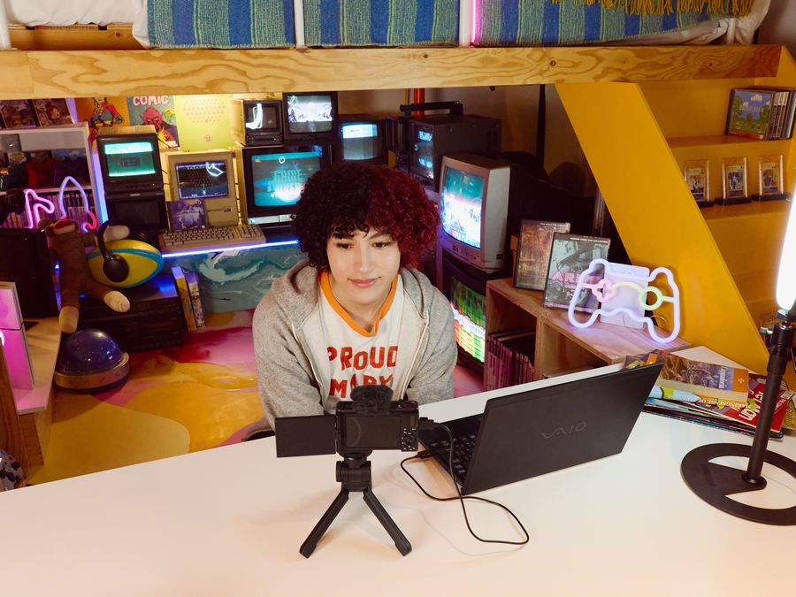 Persona filmando un video en una sala de juegos retro con varias pantallas.