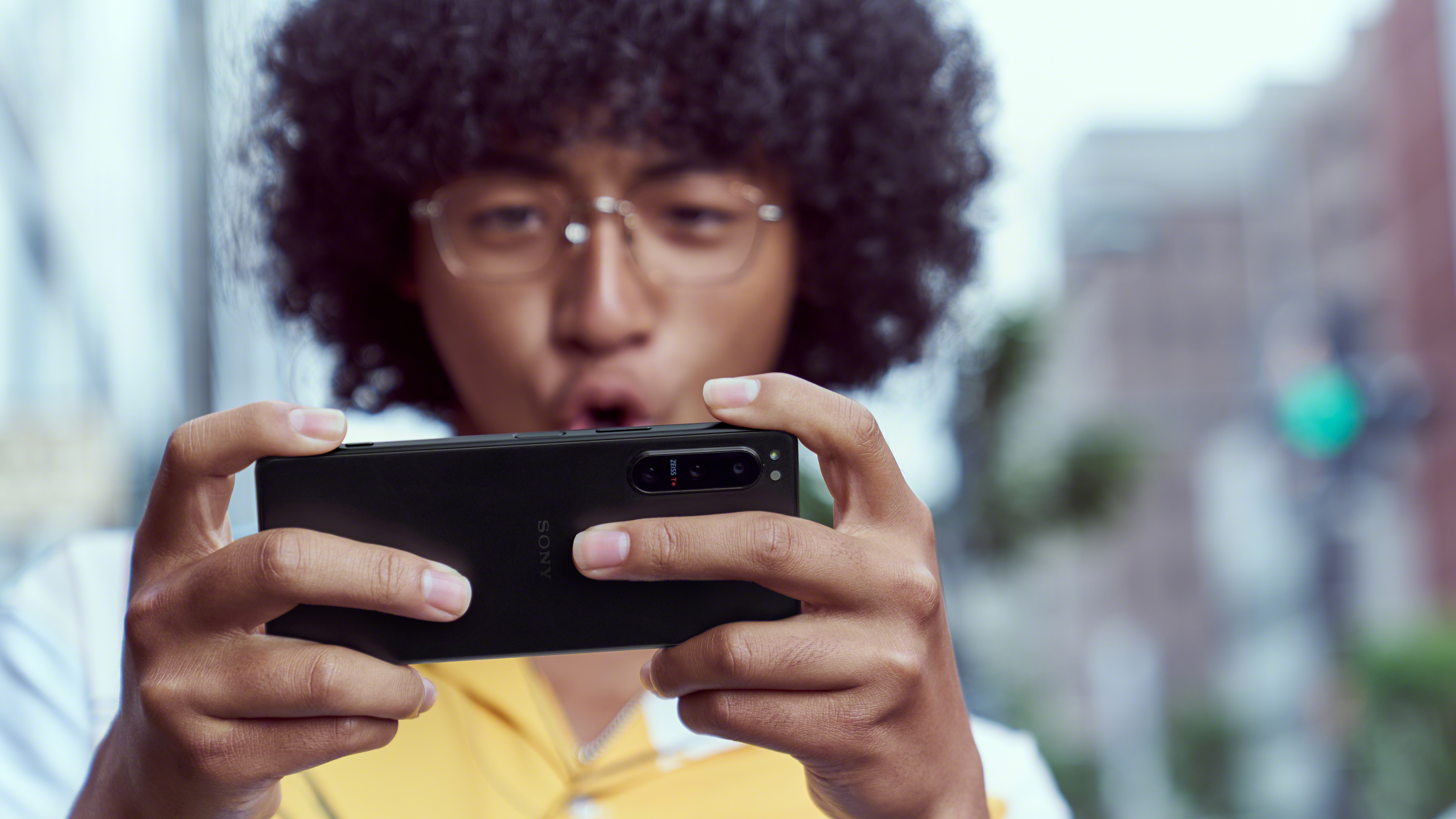 Mann hält ein schwarzes Sony-Telefon und schaut auf den Bildschirm. Verschwommener Hintergrund.