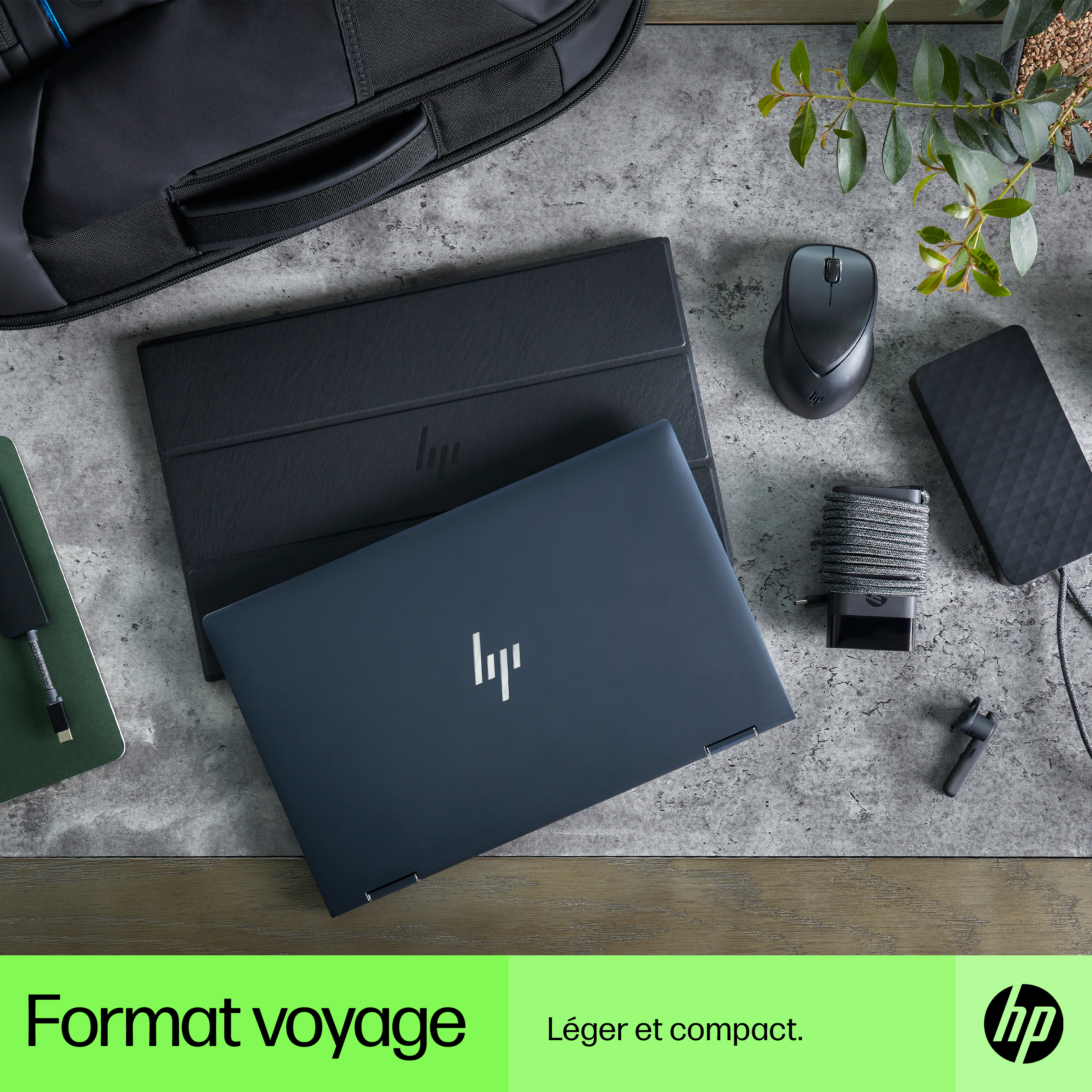 Laptop, mouse, charger, and accessories on a gray surface. The laptop is dark blue.