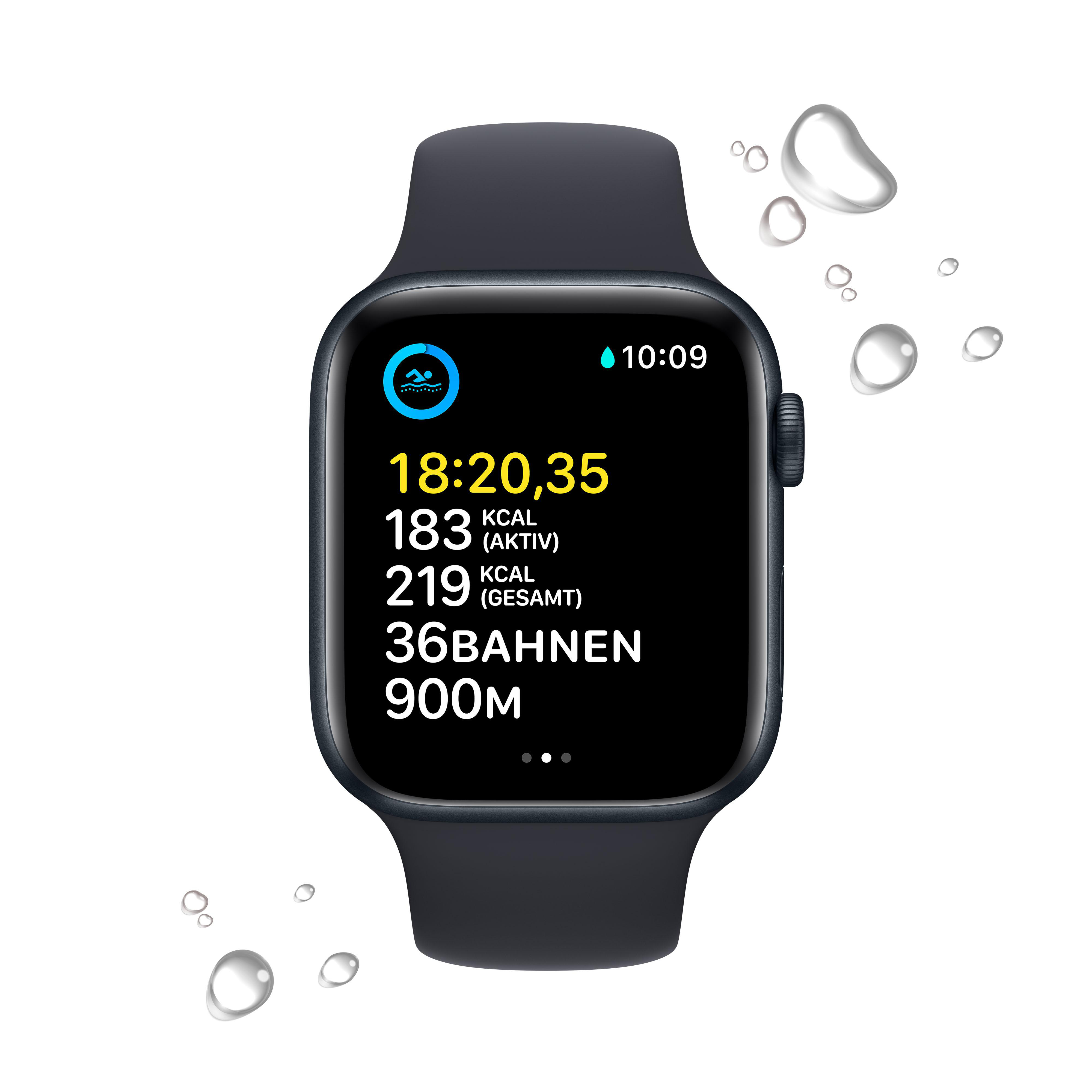 Eine schwarze Smartwatch mit Daten auf dem Bildschirm, umgeben von Wassertropfen, vor weißem Hintergrund.