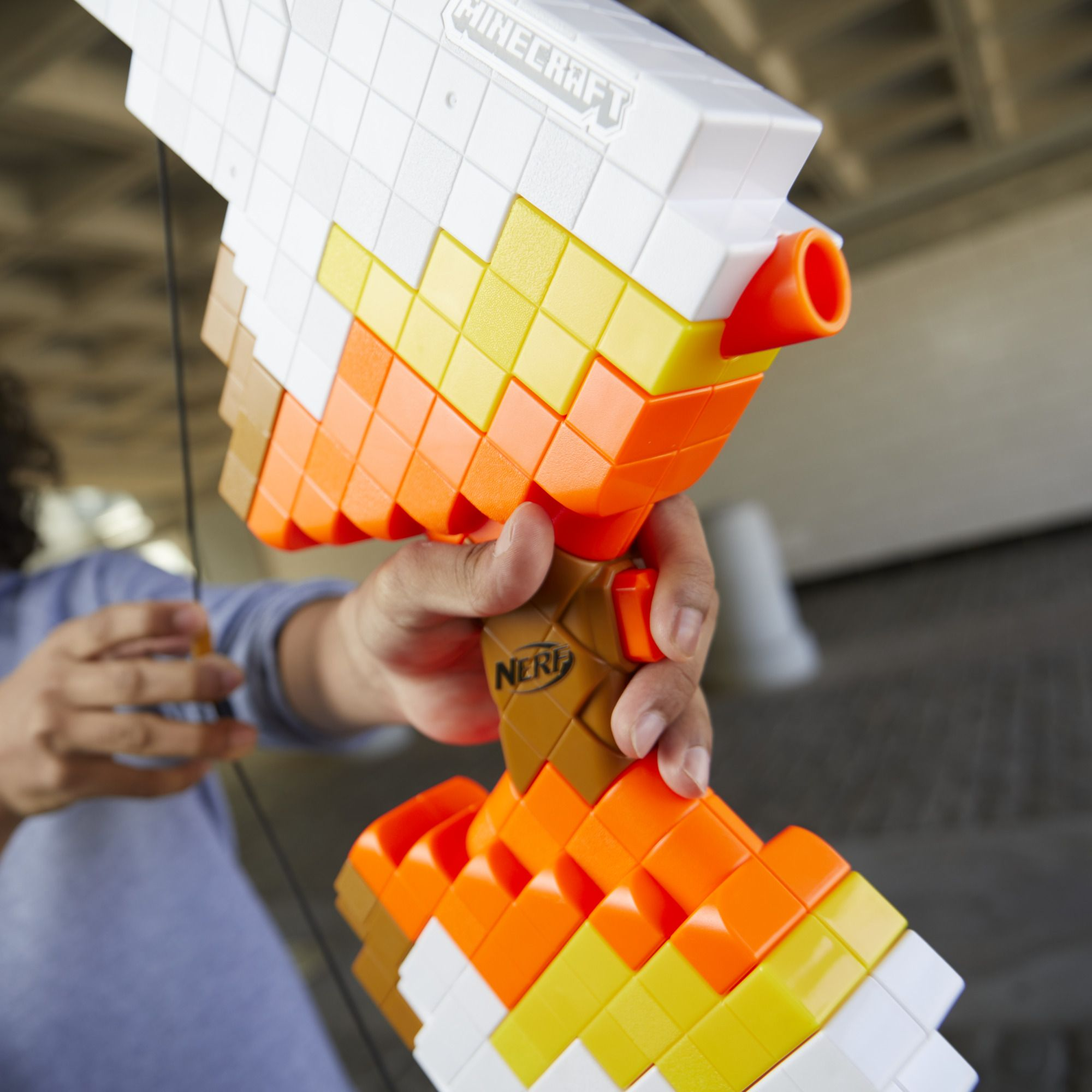 Minecraft Nerf Bogenpistole in der Hand, weißes, oranges und braunes Design.