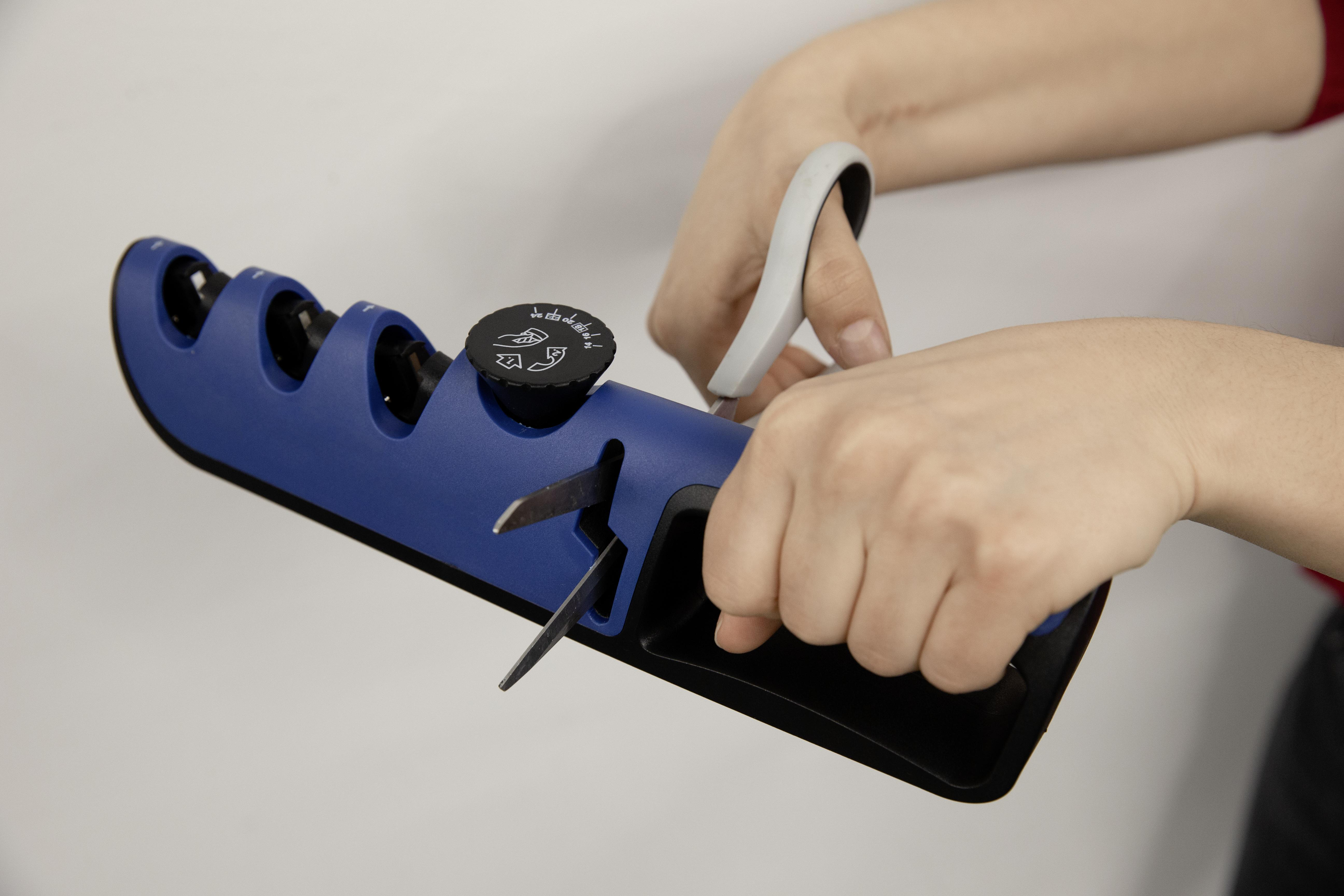 Eine Person benutzt einen blauen Messerschärfer. Hände halten den Schärfer und ein Messer.