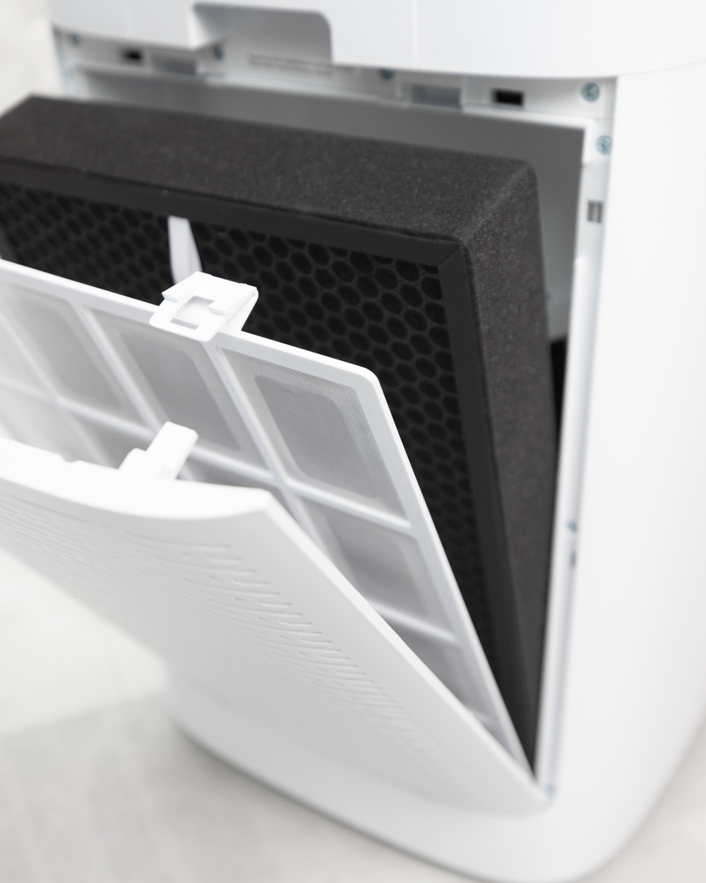 Purificateur d'air blanc avec filtre retiré. Porte ouverte révèle un filtre noir.