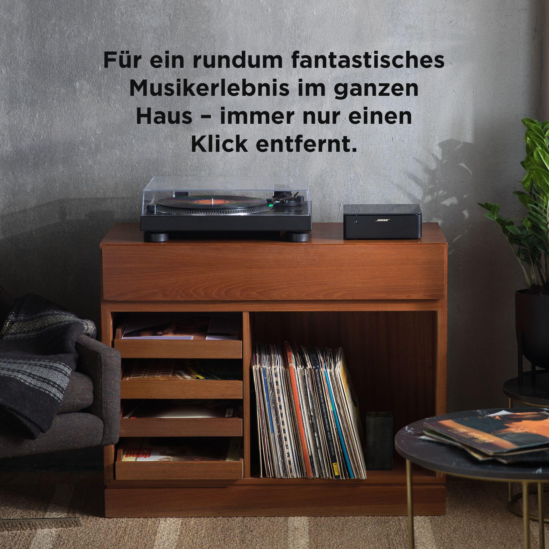 Plattenspieler und Lautsprecher auf einem Holzschrank, Schallplatten im Regal.