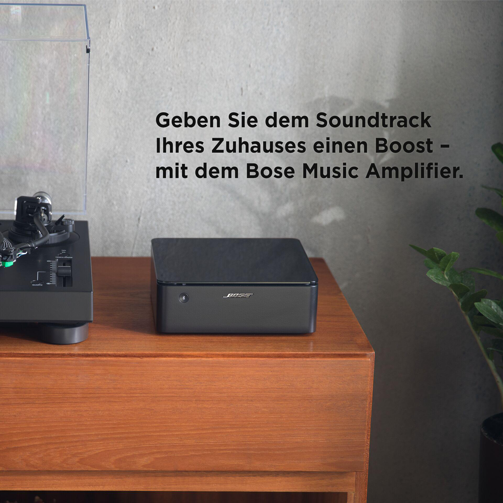 Ein Bose Musikverstärker und Plattenspieler auf einer Holzoberfläche, mit einer Pflanze.