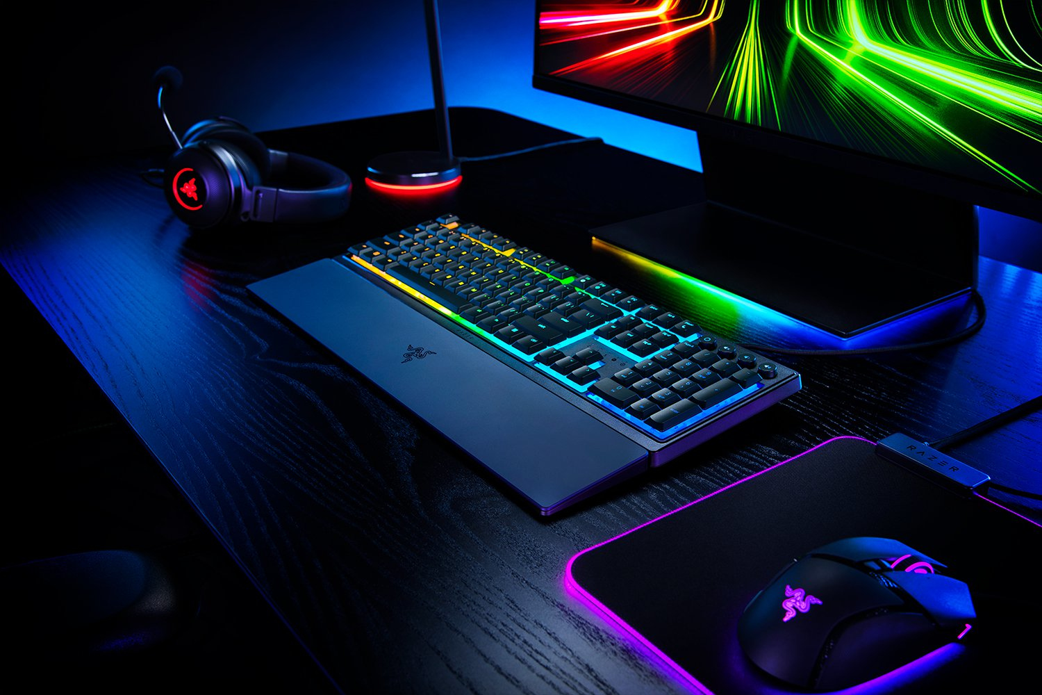 Gaming setup with keyboard, mouse, and monitor. Keyboard has colored lights.