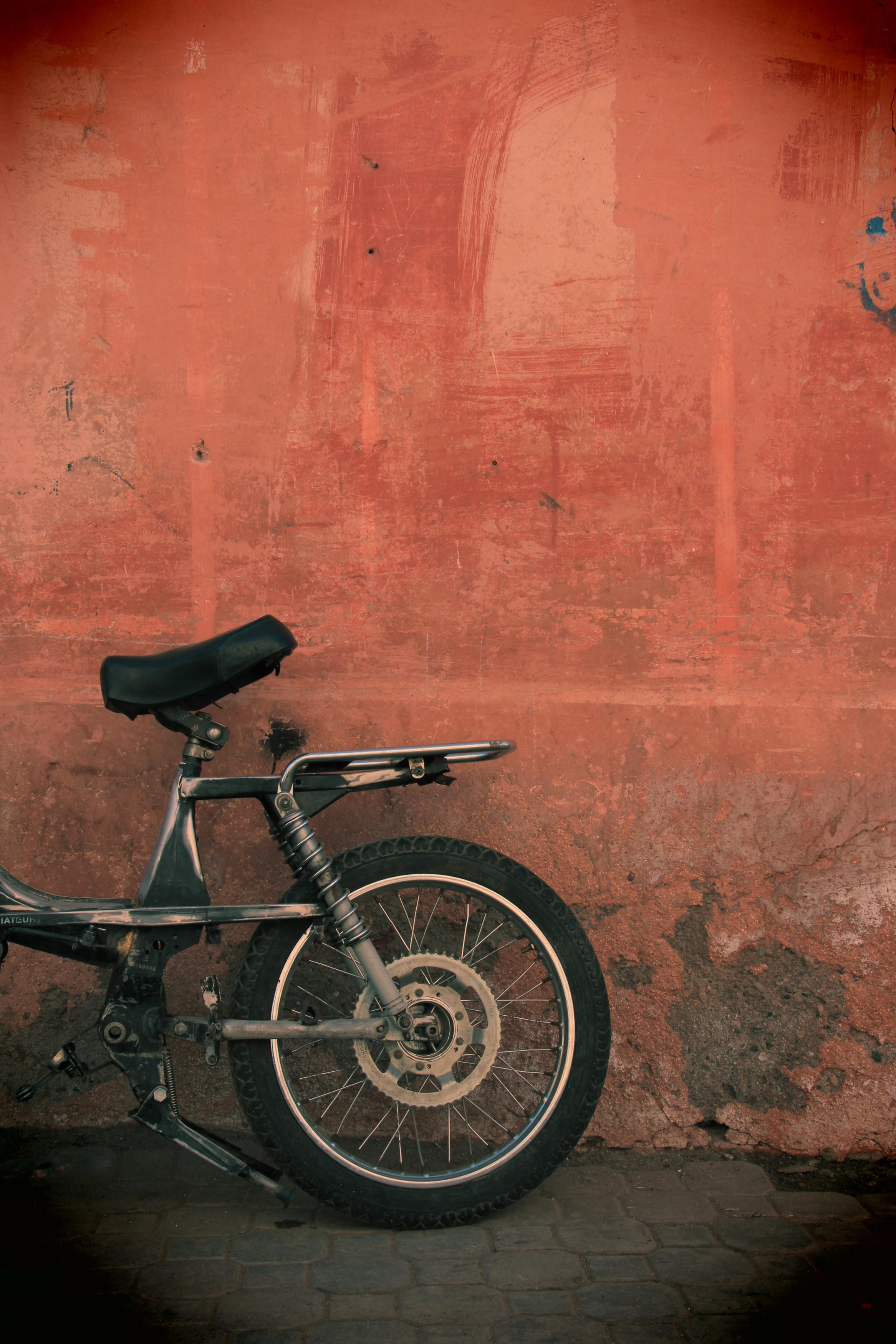 Motorrad vor einer rot-orangen Wand geparkt. Das Fahrrad ist schwarz und silber.