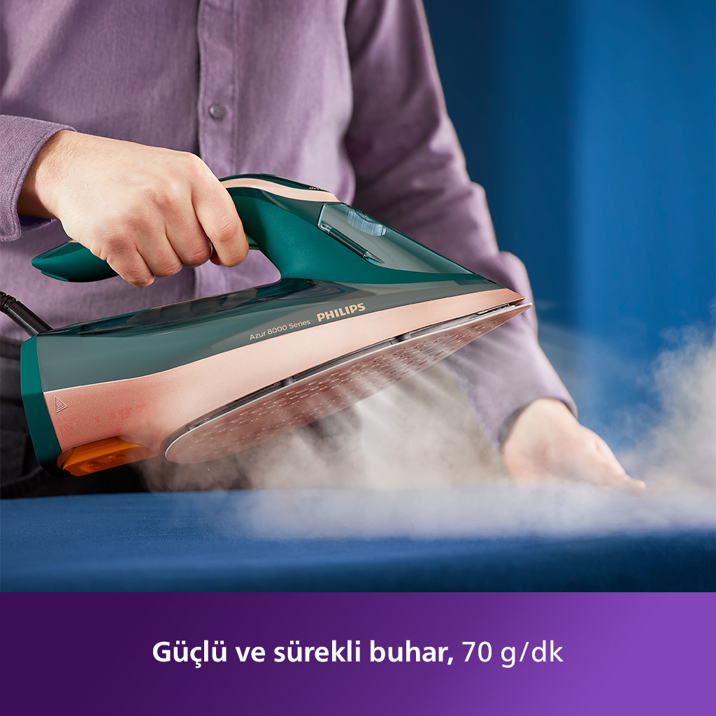 Kişi, turkuaz ve pembe altın Philips ütüsüyle mavi kumaşı ütülüyor. Kumaştan buhar yükseliyor.