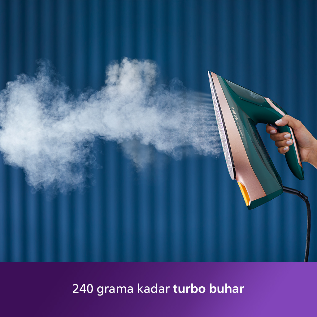 Bir kişi yeşil ve altın renkli bir ütüyle ütü yapıyor.