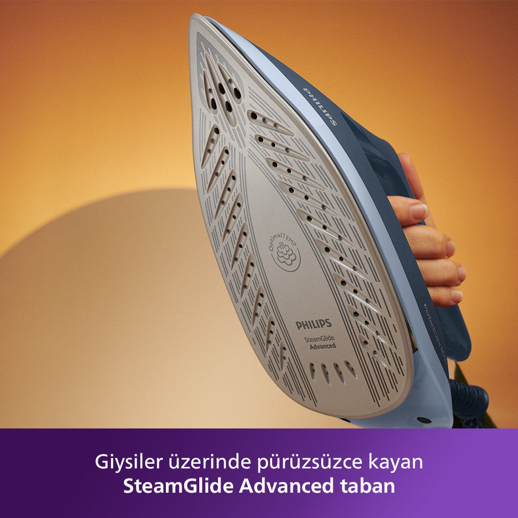Bir elin tuttuğu ütü tabanı. Bulanık turuncu bir arka plana karşı.