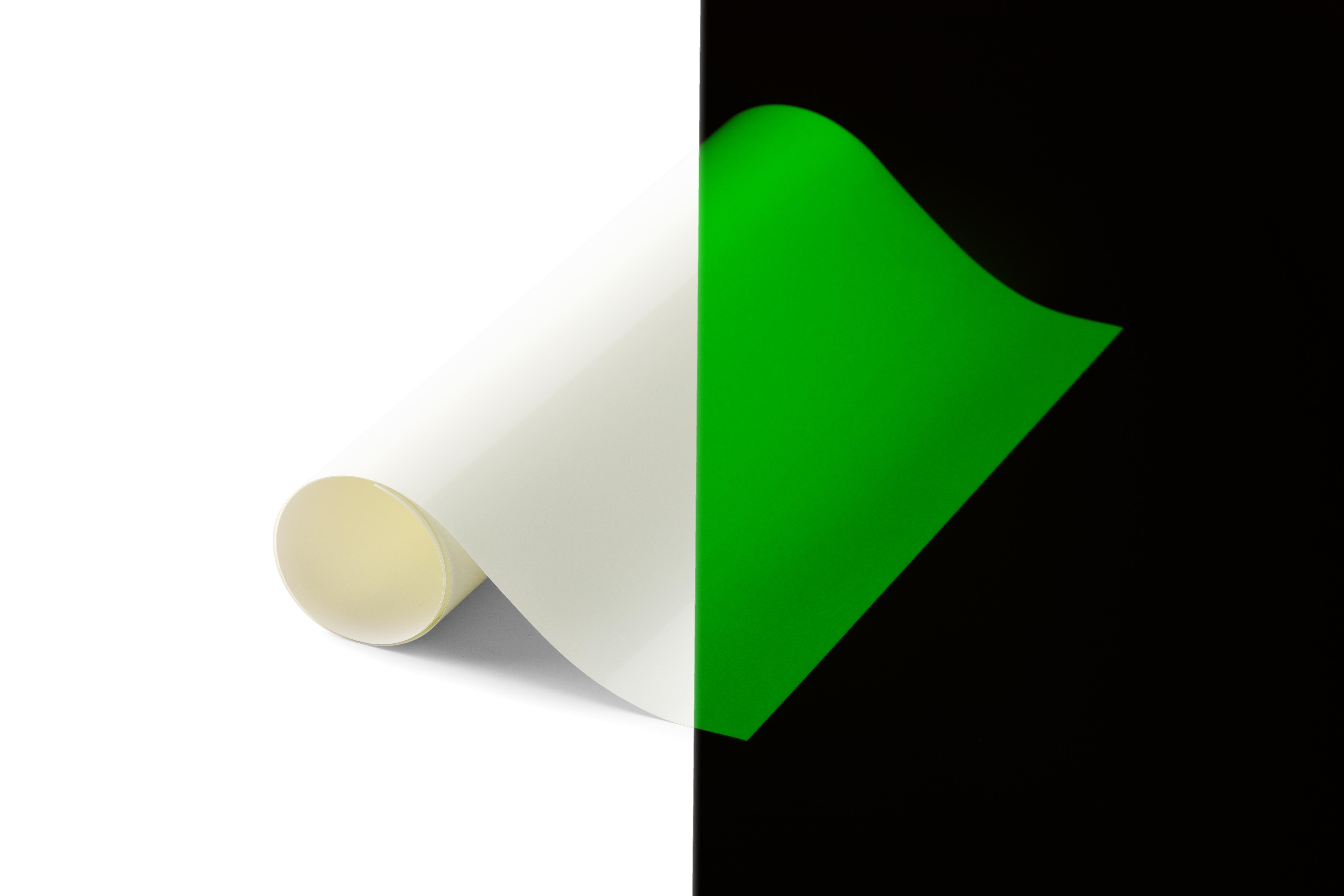 Weißes, gerolltes Papier und grünes Blatt auf schwarzem Hintergrund.