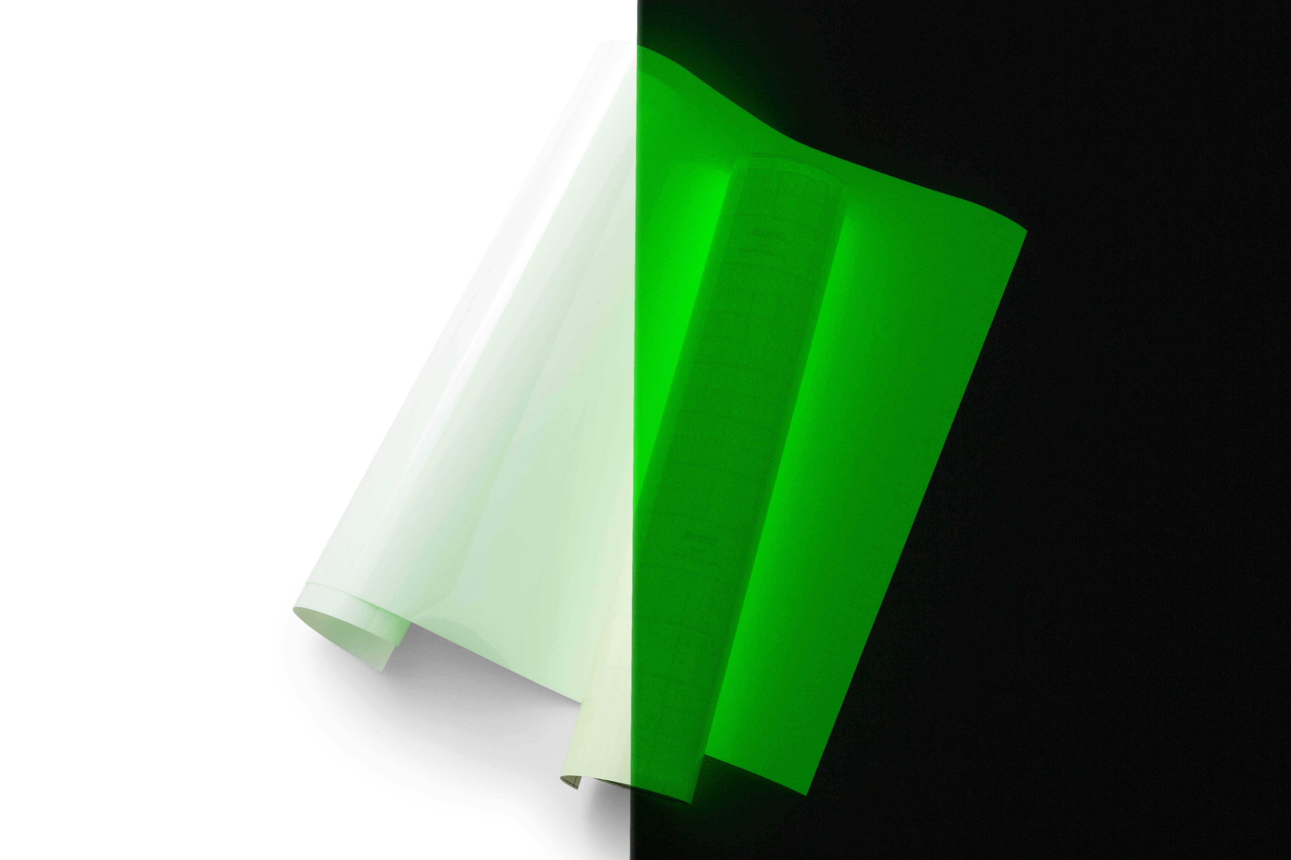 Zwei Rollen fluoreszierendes Papier, eine weiße, eine grüne, vor Schwarz-Weiß-Hintergrund.