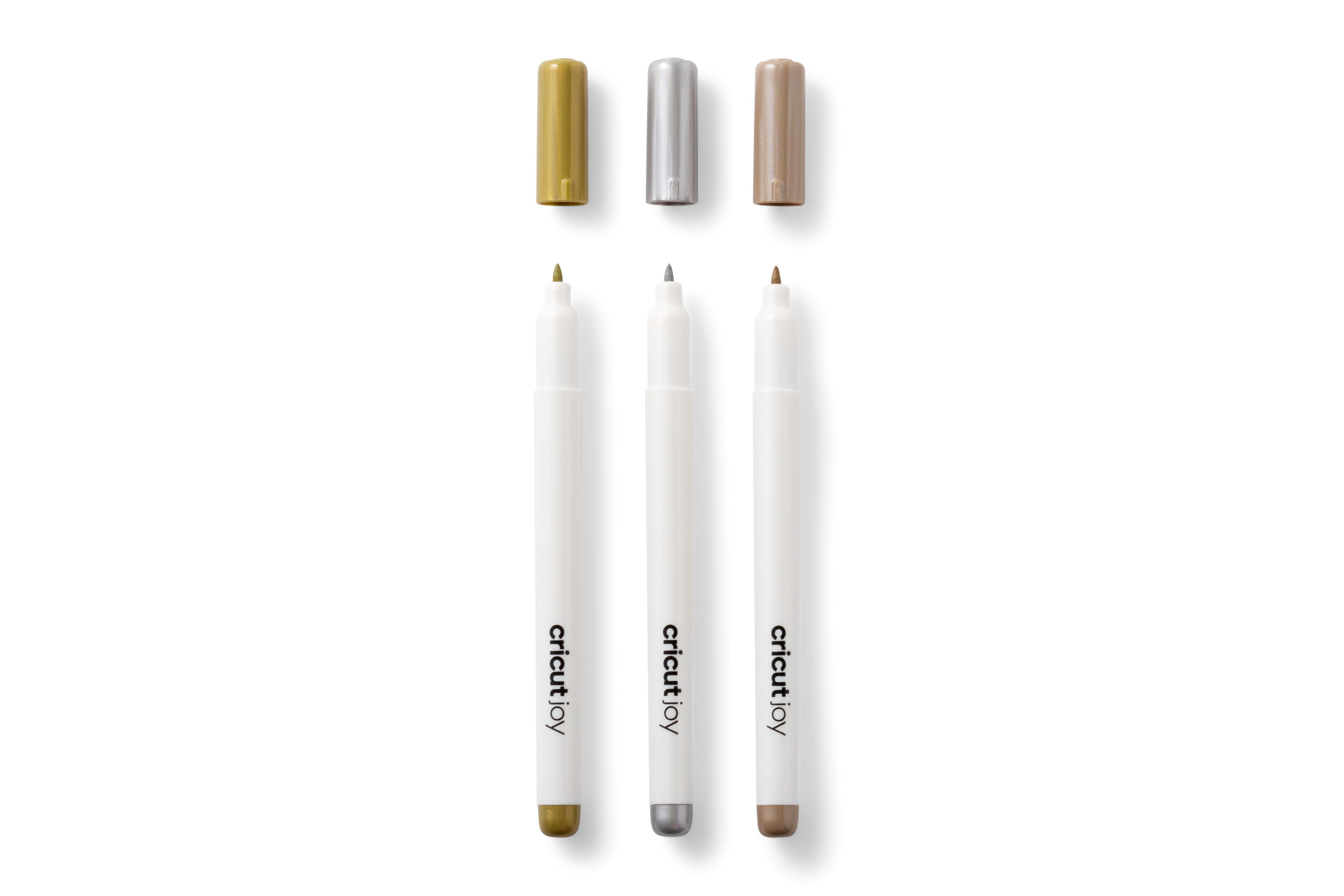 Drei weiße Cricut Joy Stifte mit Kappen. Gold, Silber und Bronze.