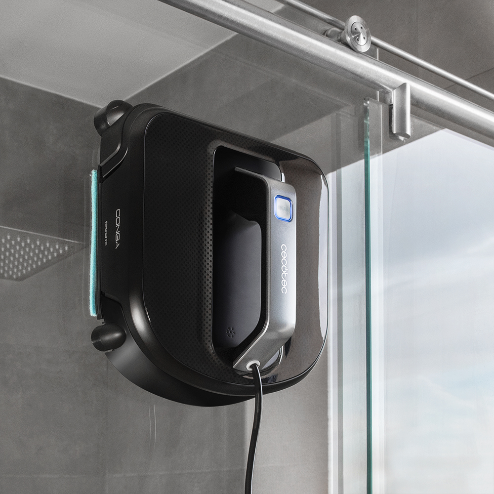 Limpiador de ventanas negro y gris adherido al cristal, con cable de alimentación.