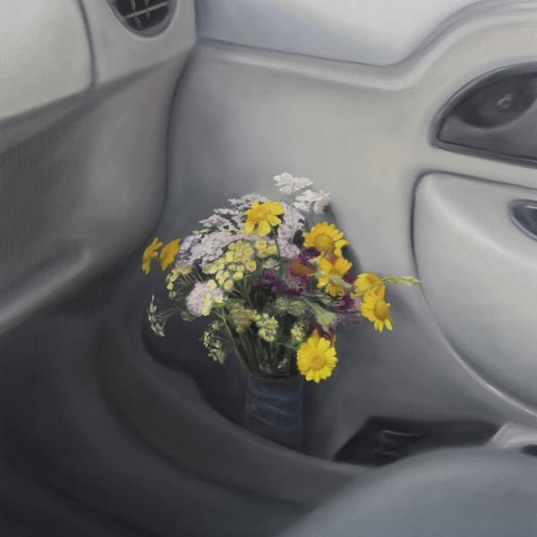 Een interieur van een auto met een vaas gele en witte bloemen in de deurklinkruimte.