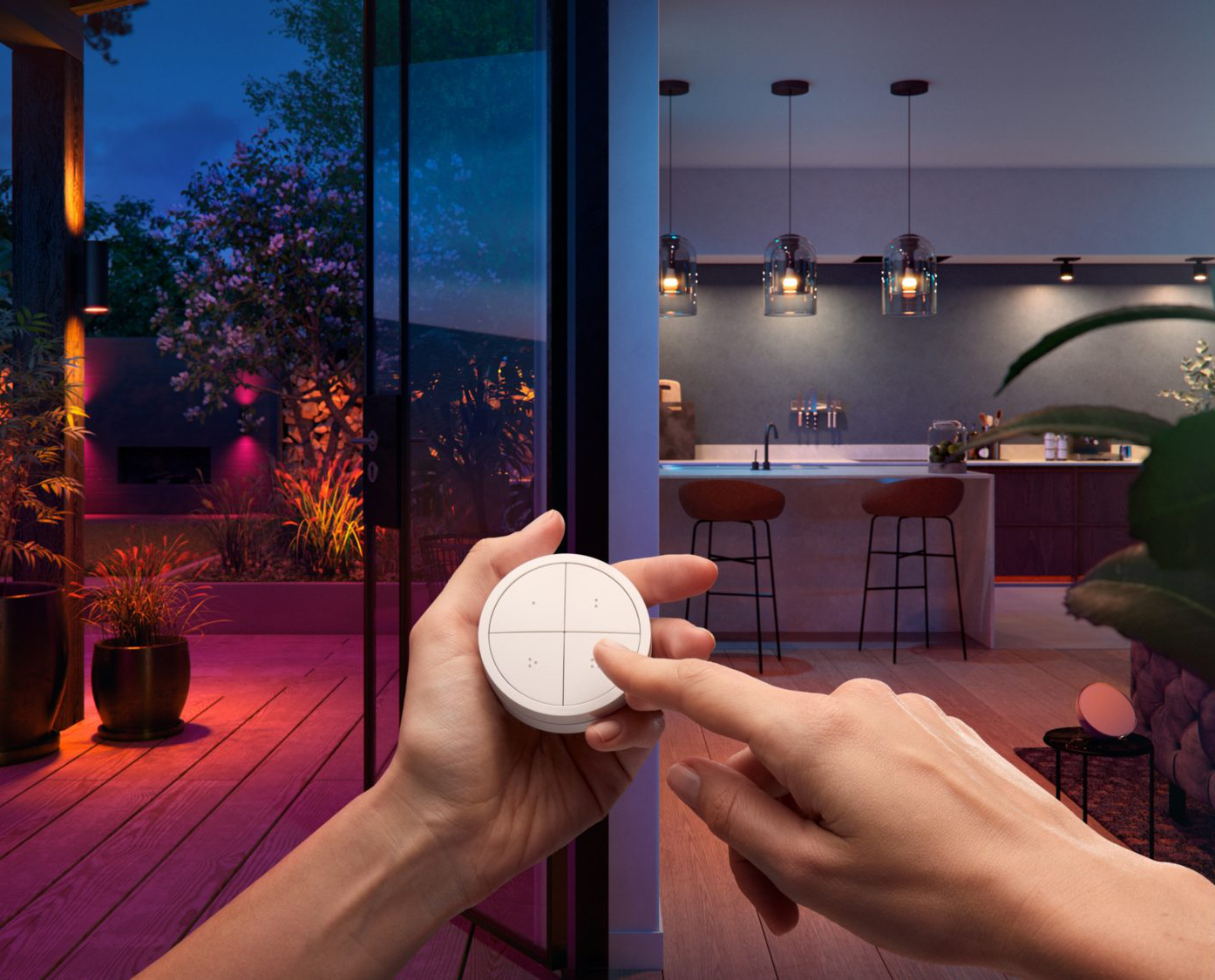 Une main actionnant un appareil domestique intelligent. La scène comprend un patio, une cuisine et un éclairage d'ambiance.