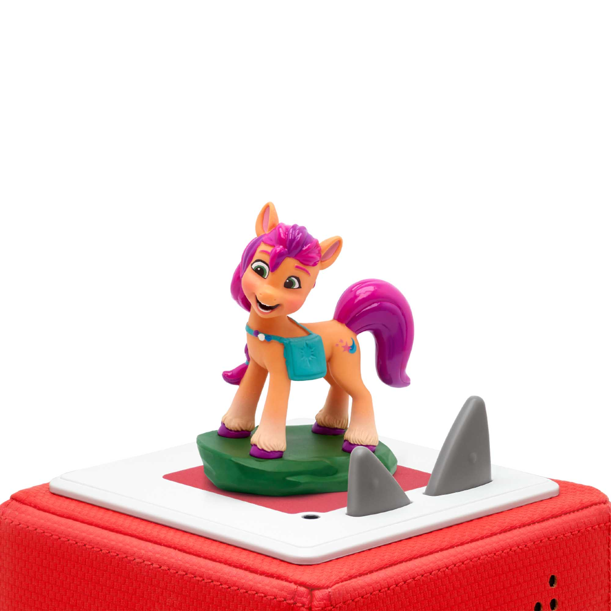 My Little Pony-Figur. Ein Pony steht auf einer grünen Oberfläche auf roter Basis, mit zwei grauen Haifischflossen.